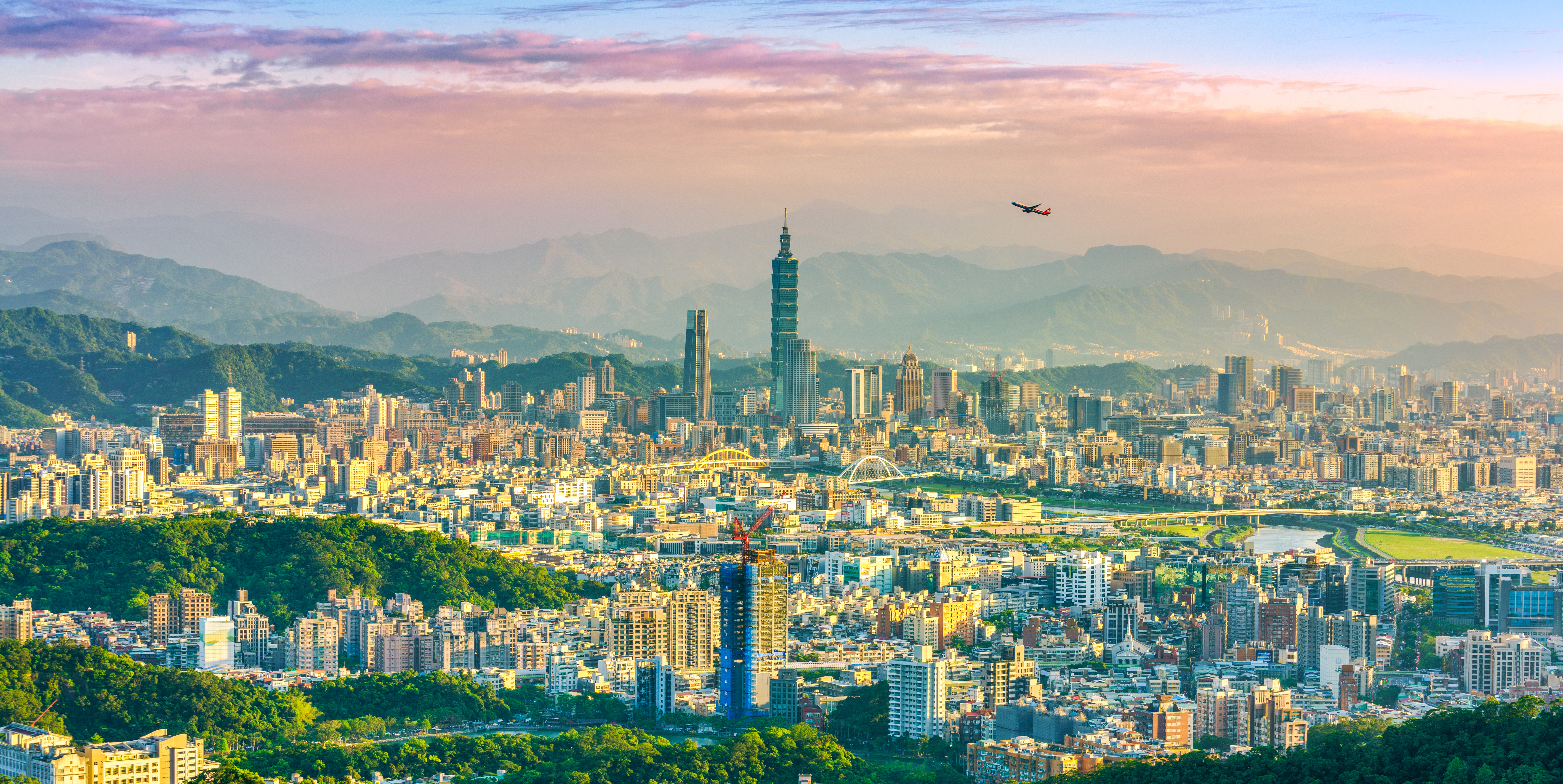Taipei City Airplane flying over Taipei city at sunset with mountains in the background