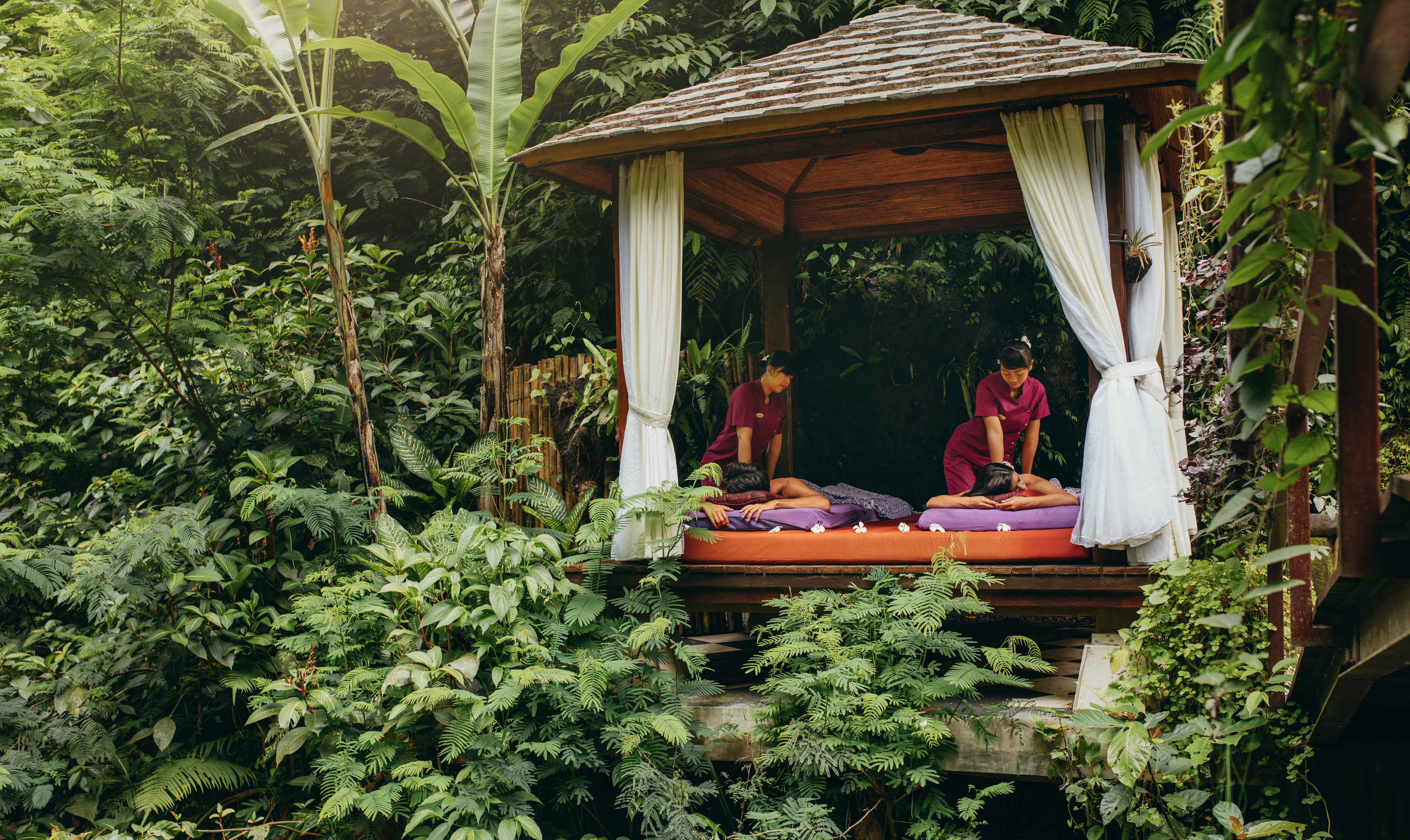 A couple enjoy massages in an outdoor gazebo in the jungle