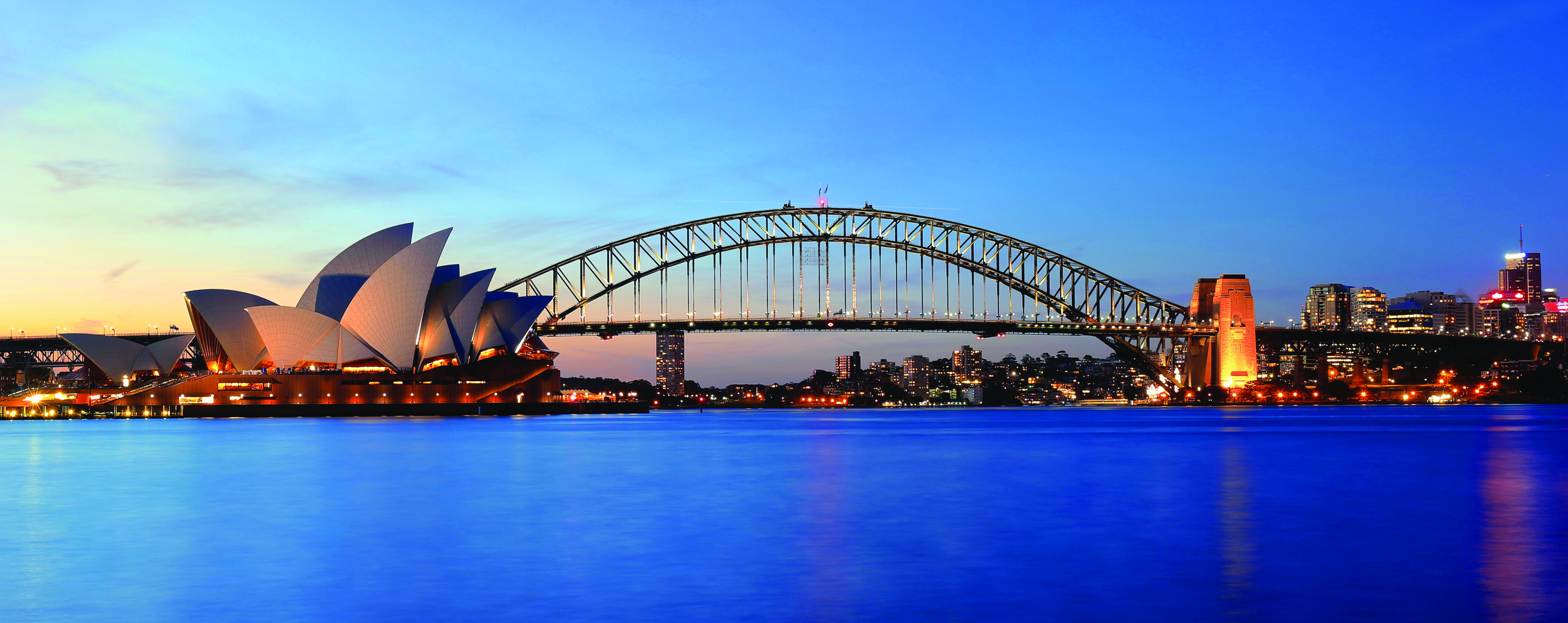 view of harbour bridge and opera house at sunset
