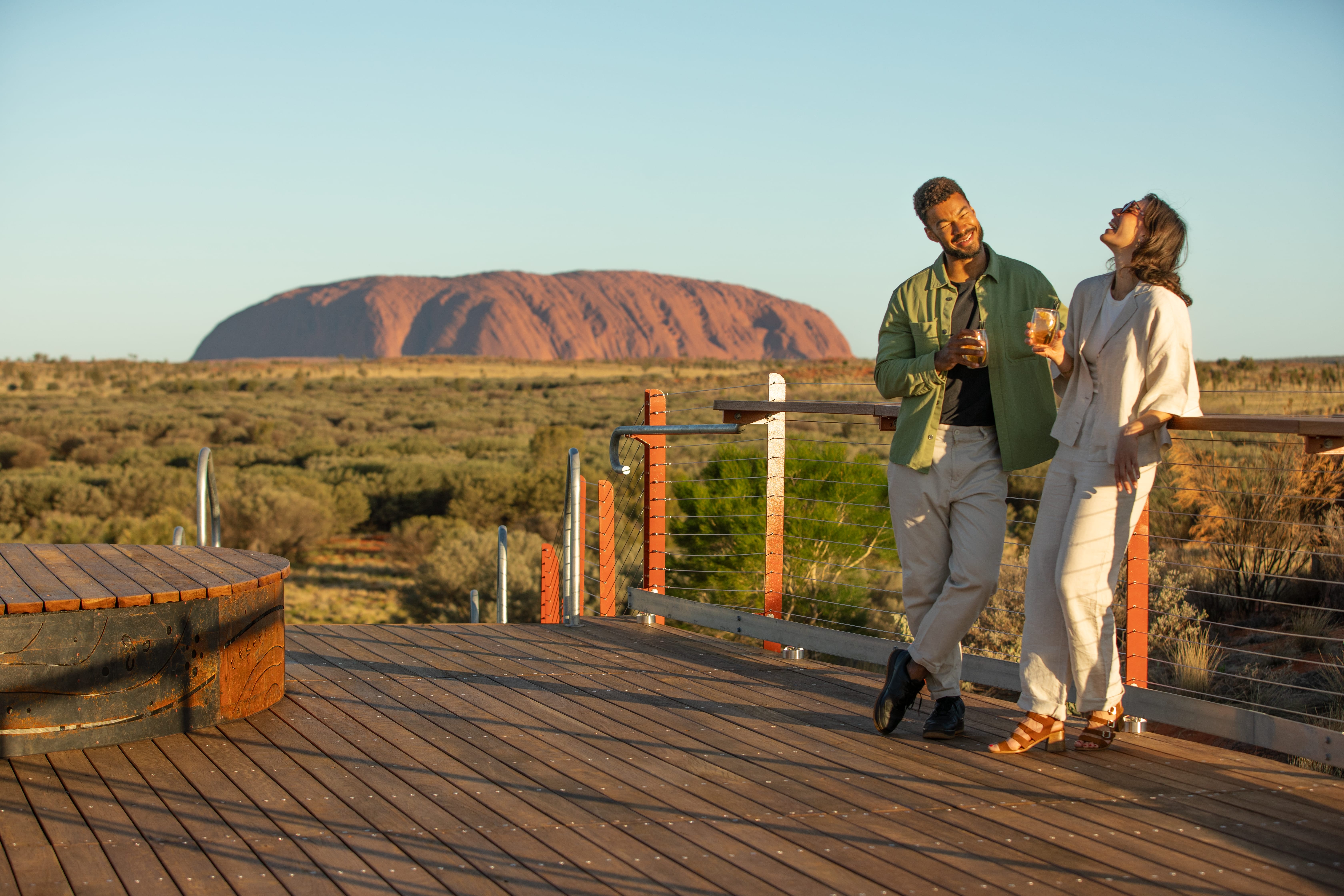 a young couple enjoying drinks on an Australia vacation while Uluru/Ayers Rock is in the background