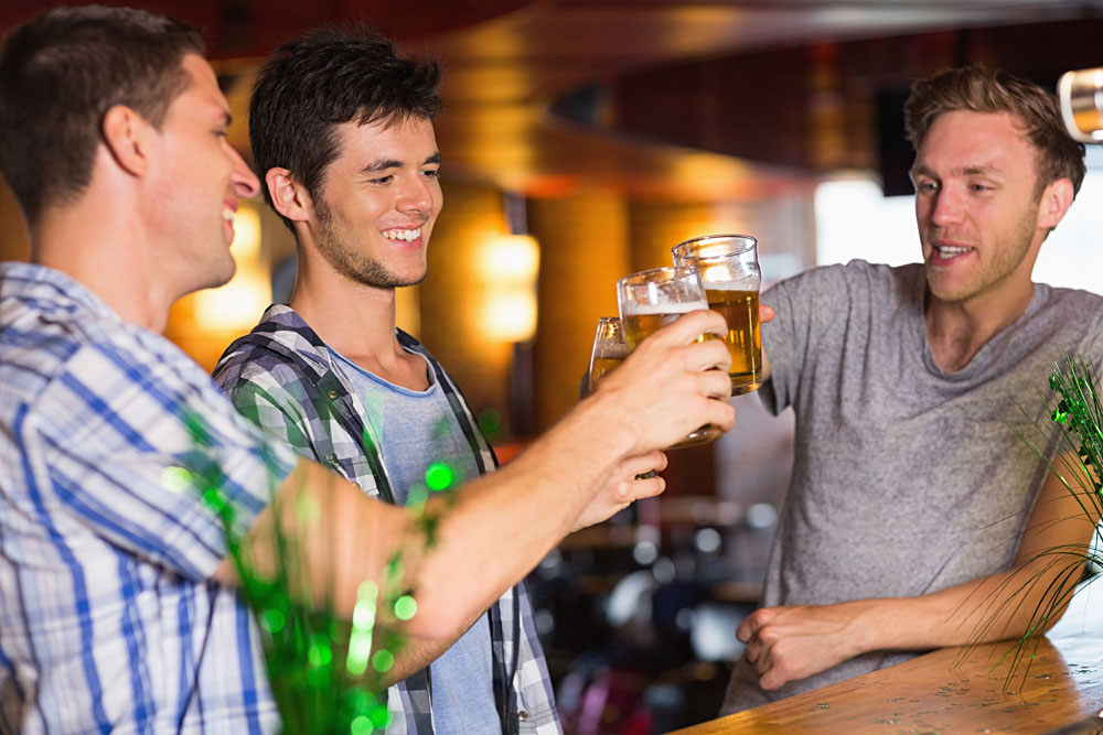 Happy Male Friends Toasting with Beer on St Patricks Day in a Bar