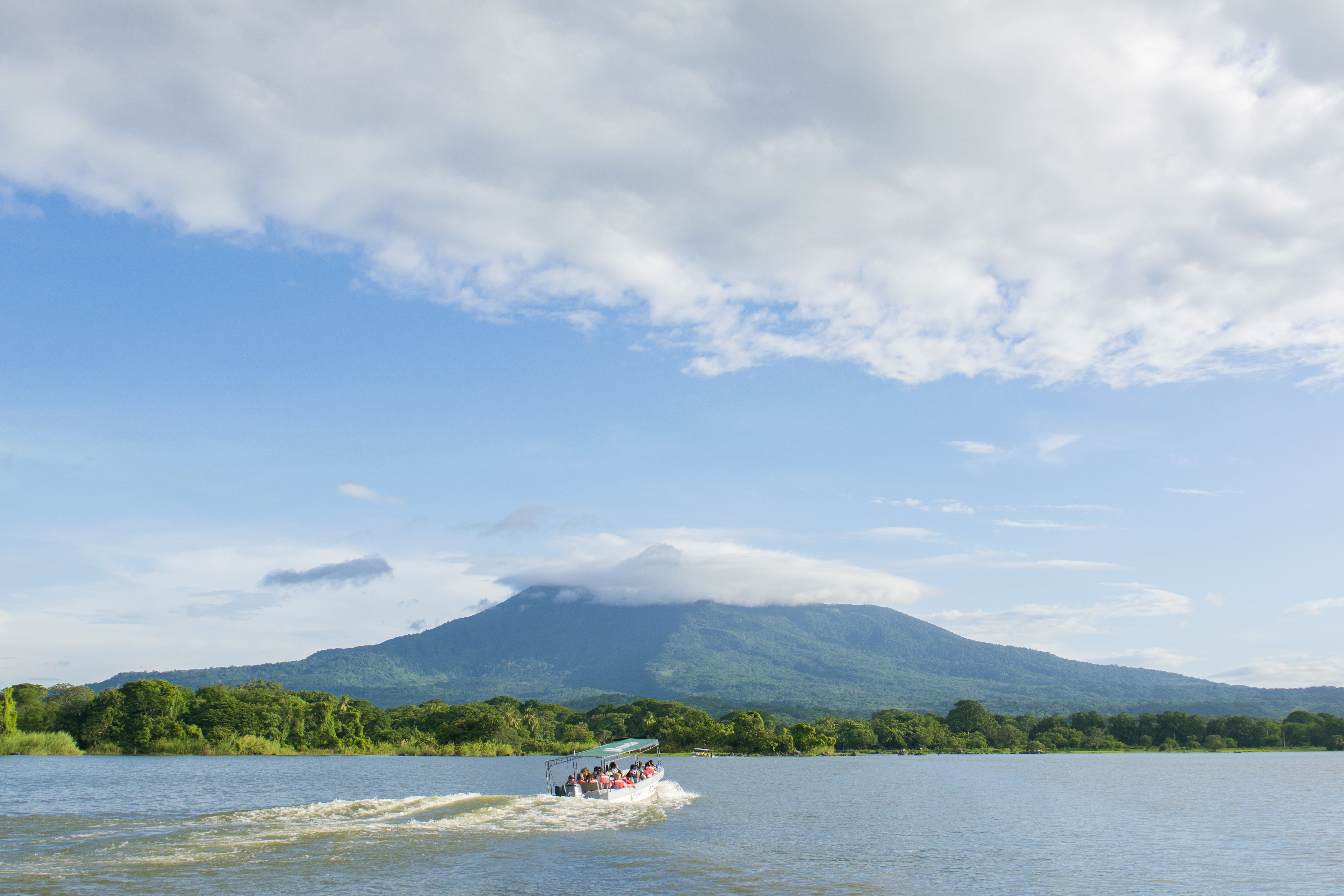A boat races across a lake in front of Volcan Mombacho in Nicaragua.