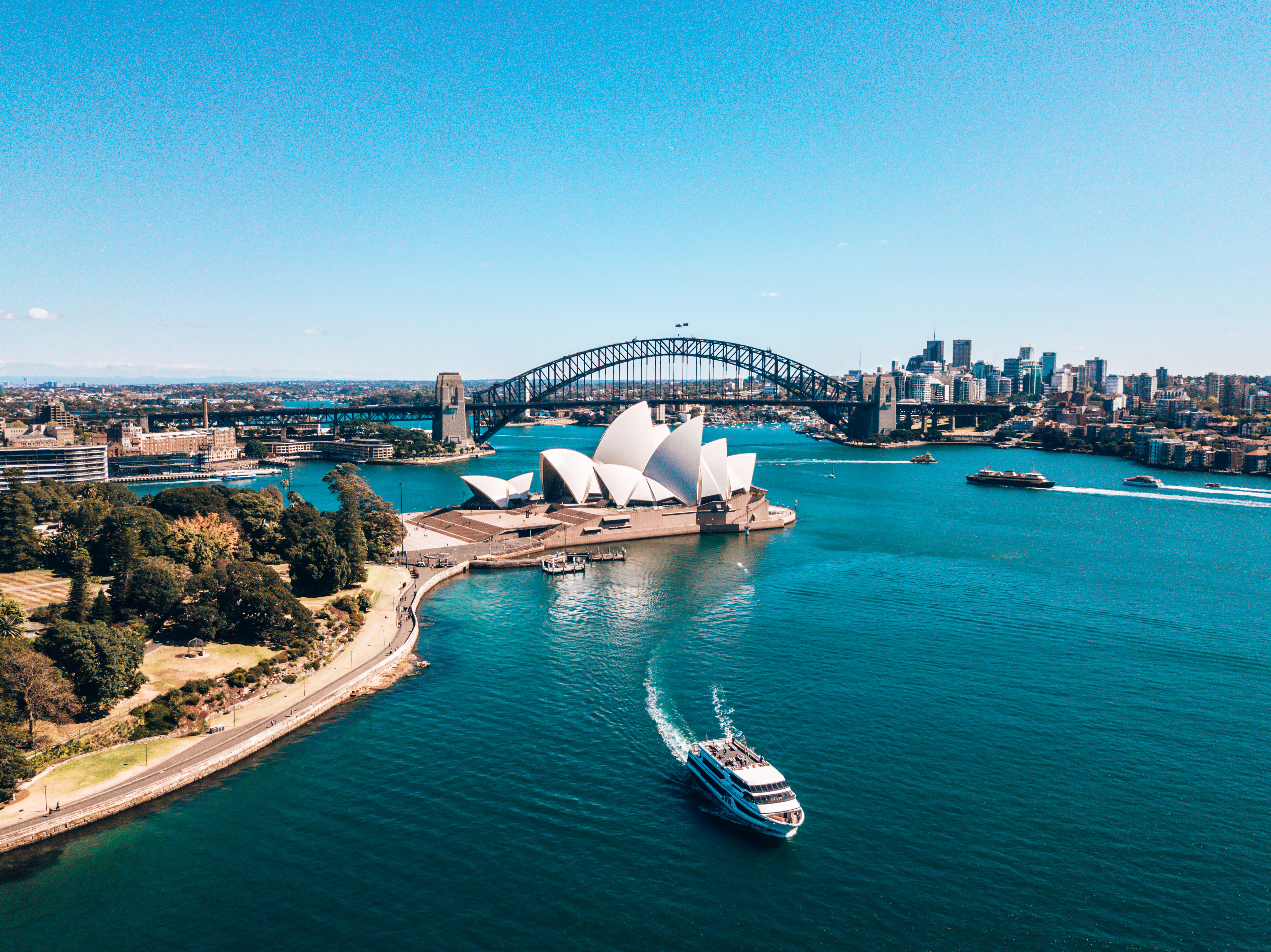 aerial view of harbour and opera house with boat crossing the water