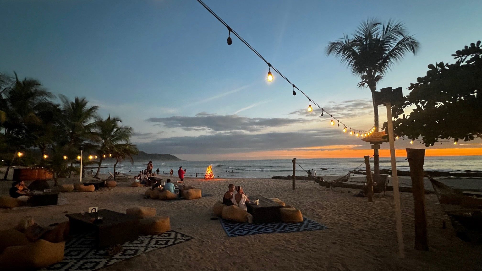 beach at sunset with trees and people lounging