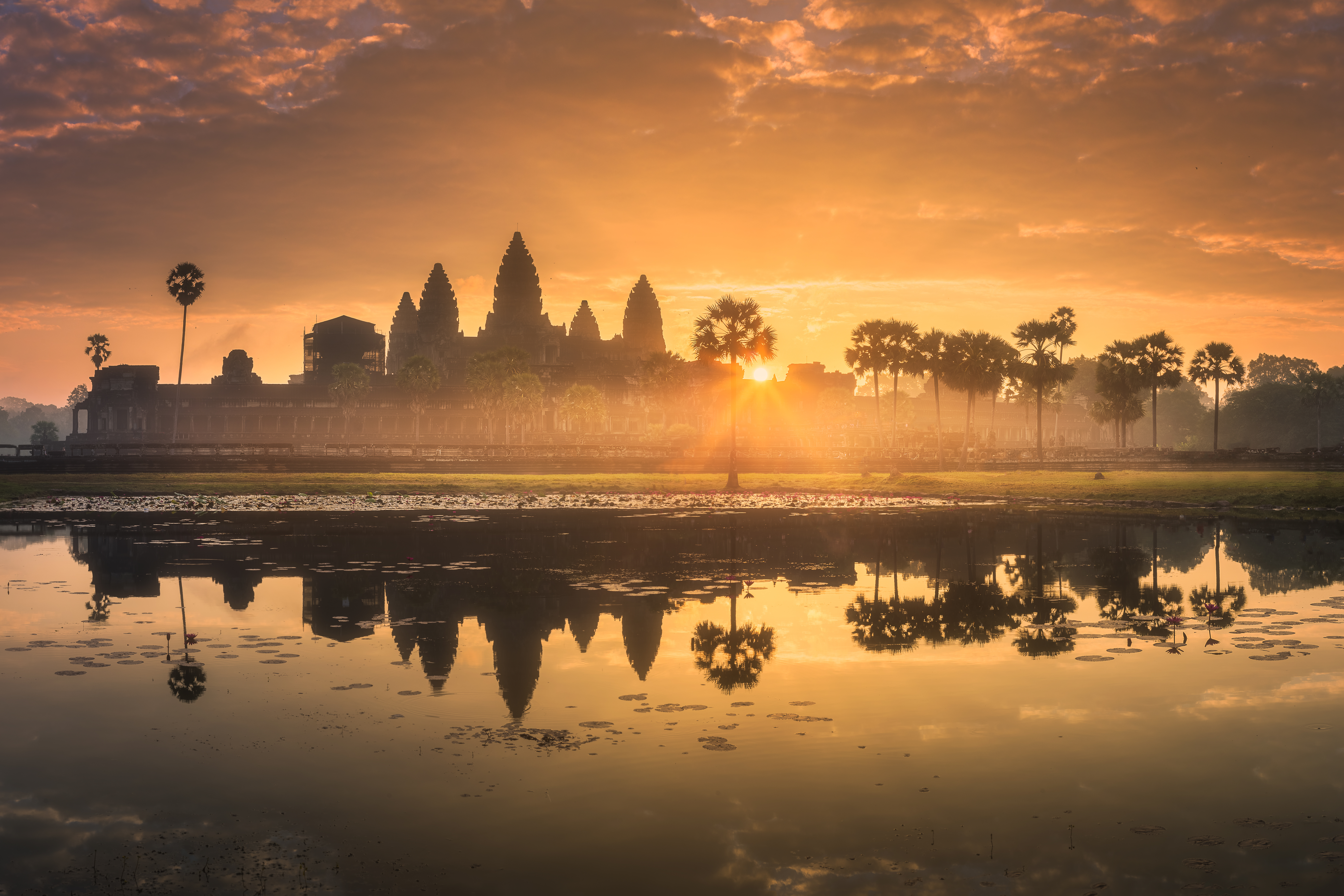 sunrise over a temple with water reflecting in foreground