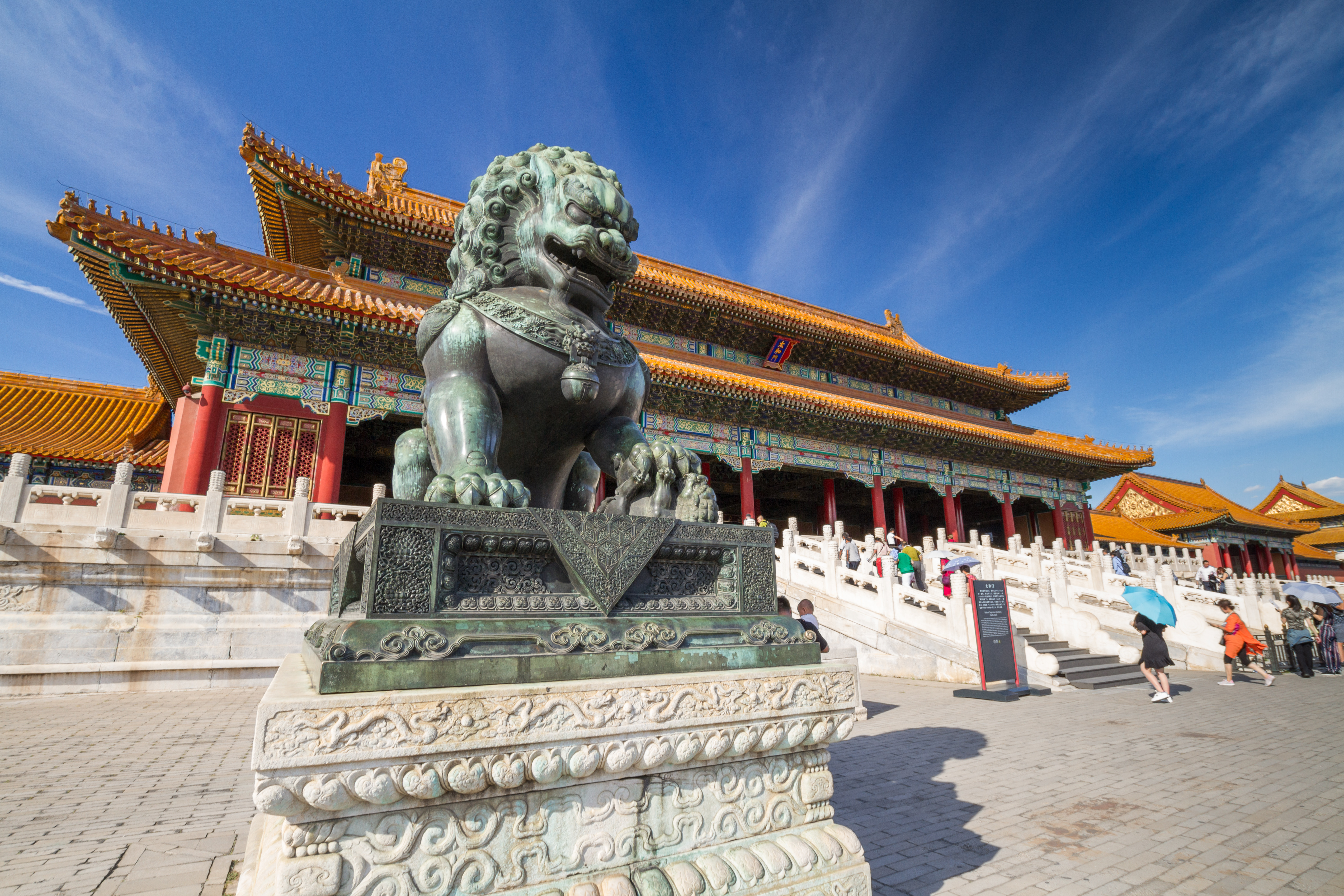 statue of a lion outside a massive chinese palace
