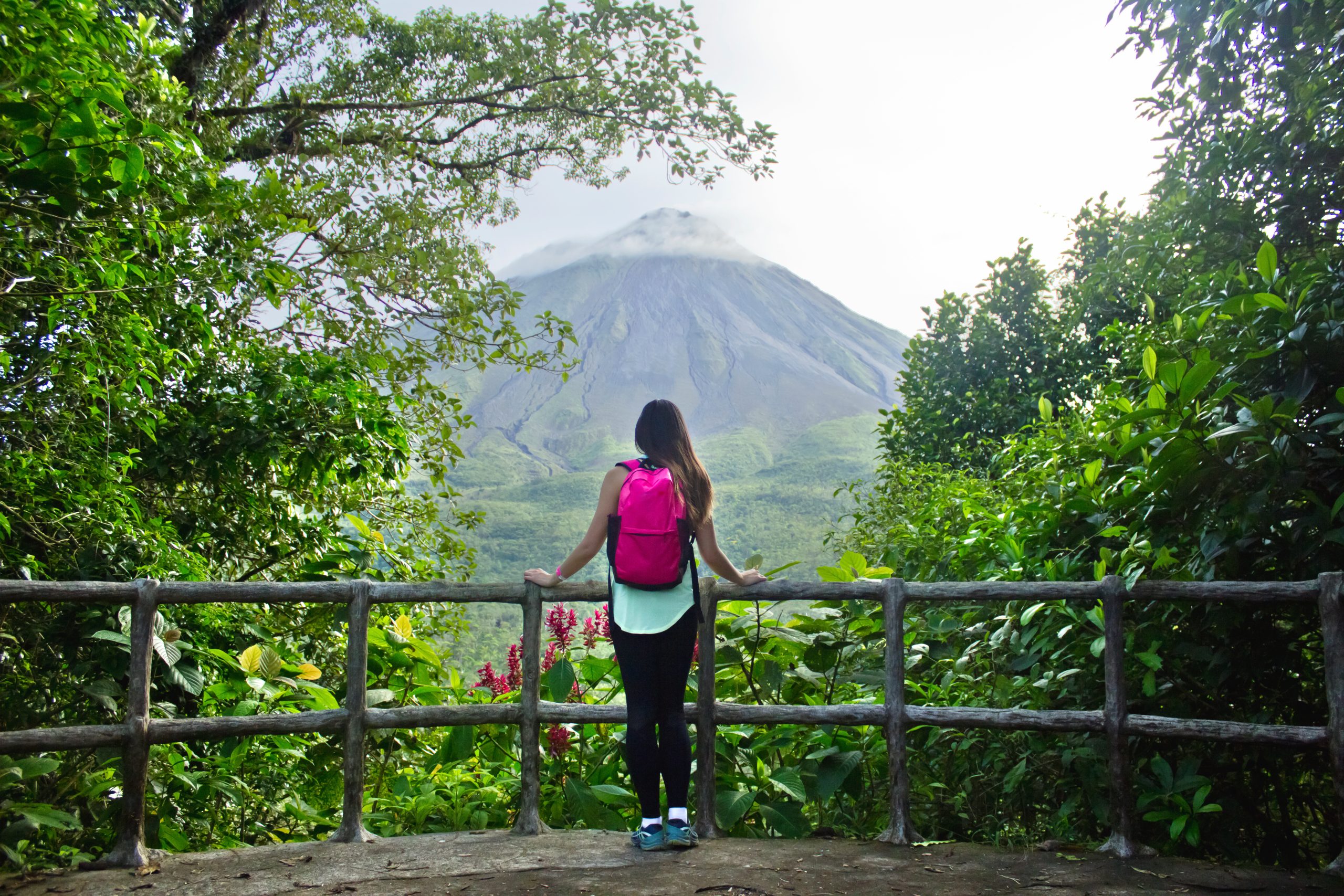 hiker leaning on railing looking at volcano