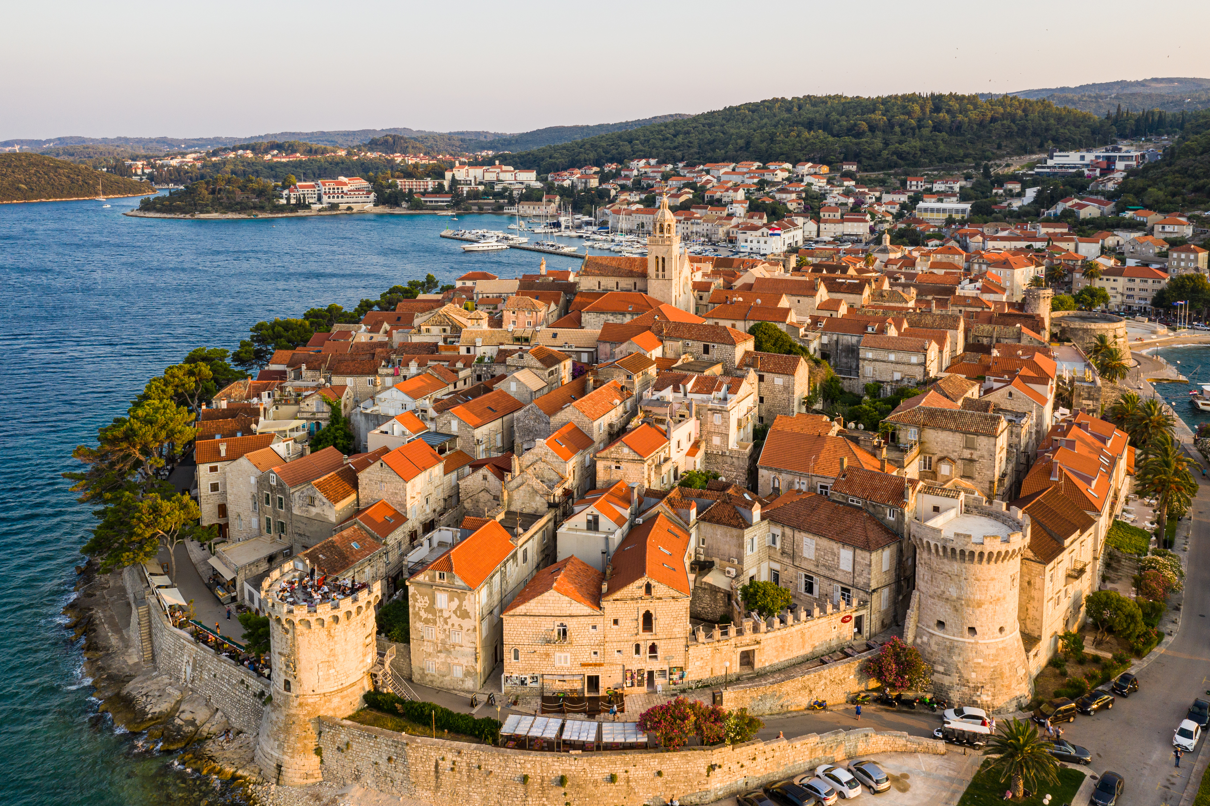 an aerial view of red-roofed homes and medieval walls surrounding the Croatian city of Korcula