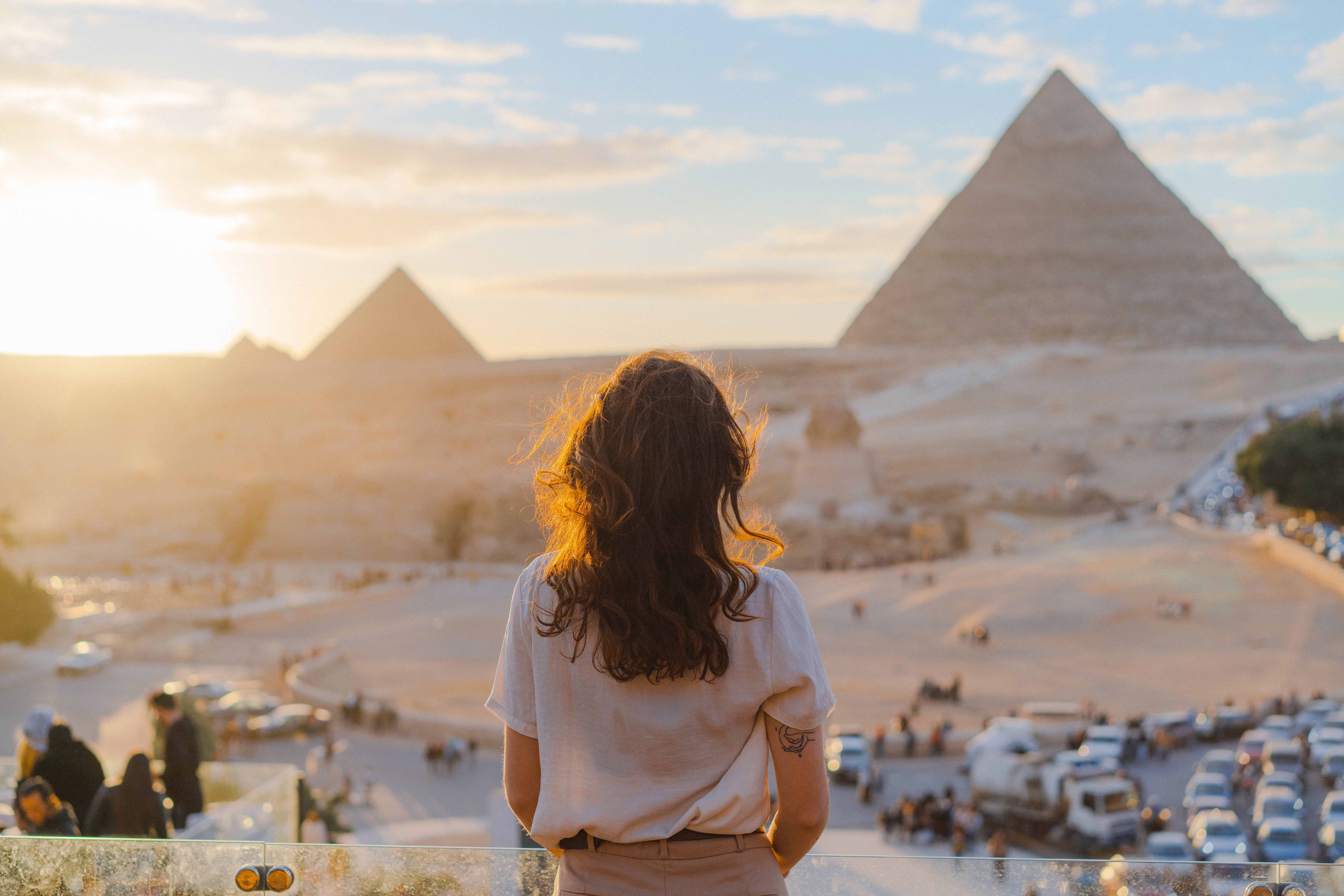 woman standing on balcony overlooking the pyramids in the distance