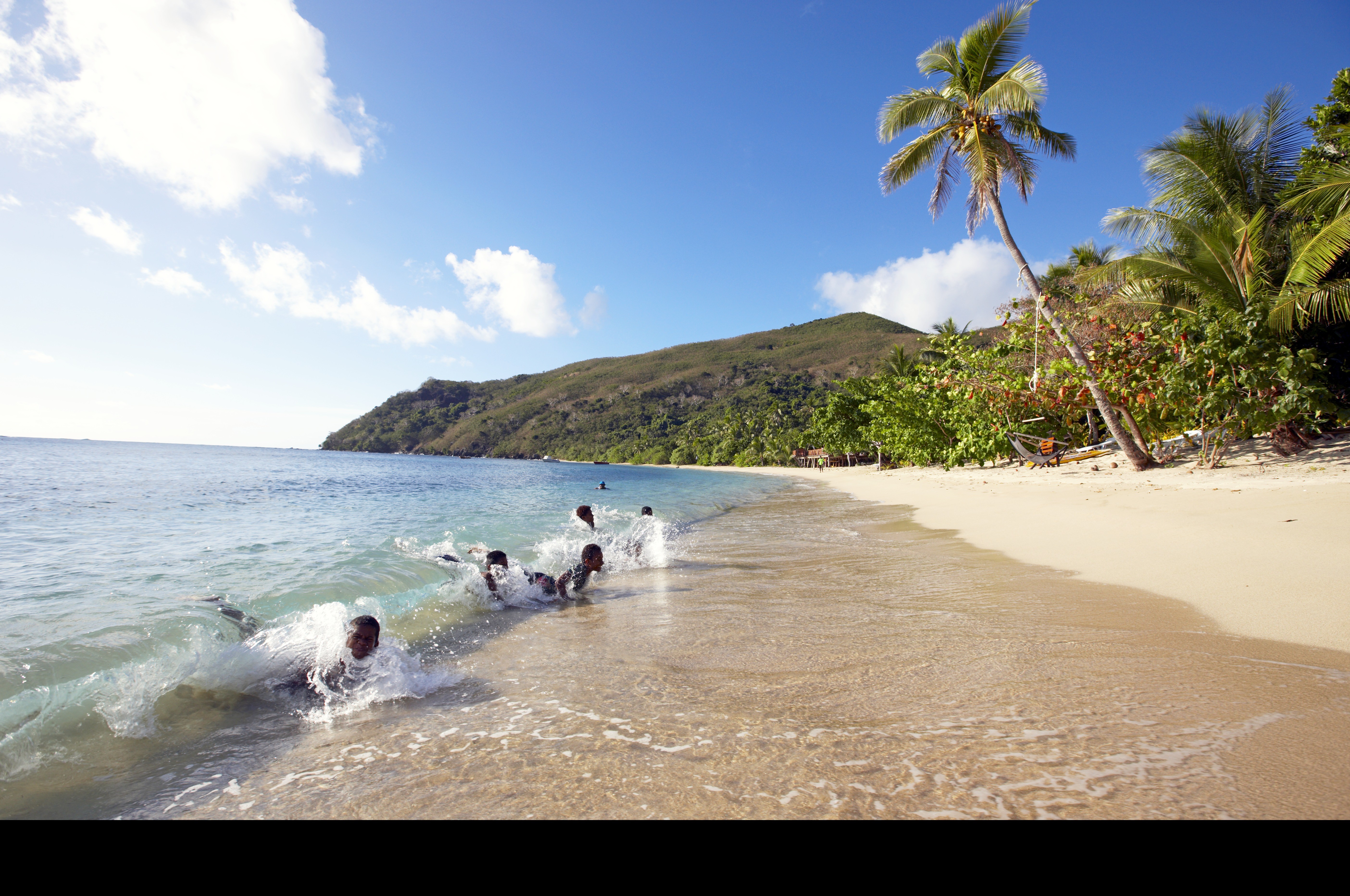 children playing in the surf on a white sand beach