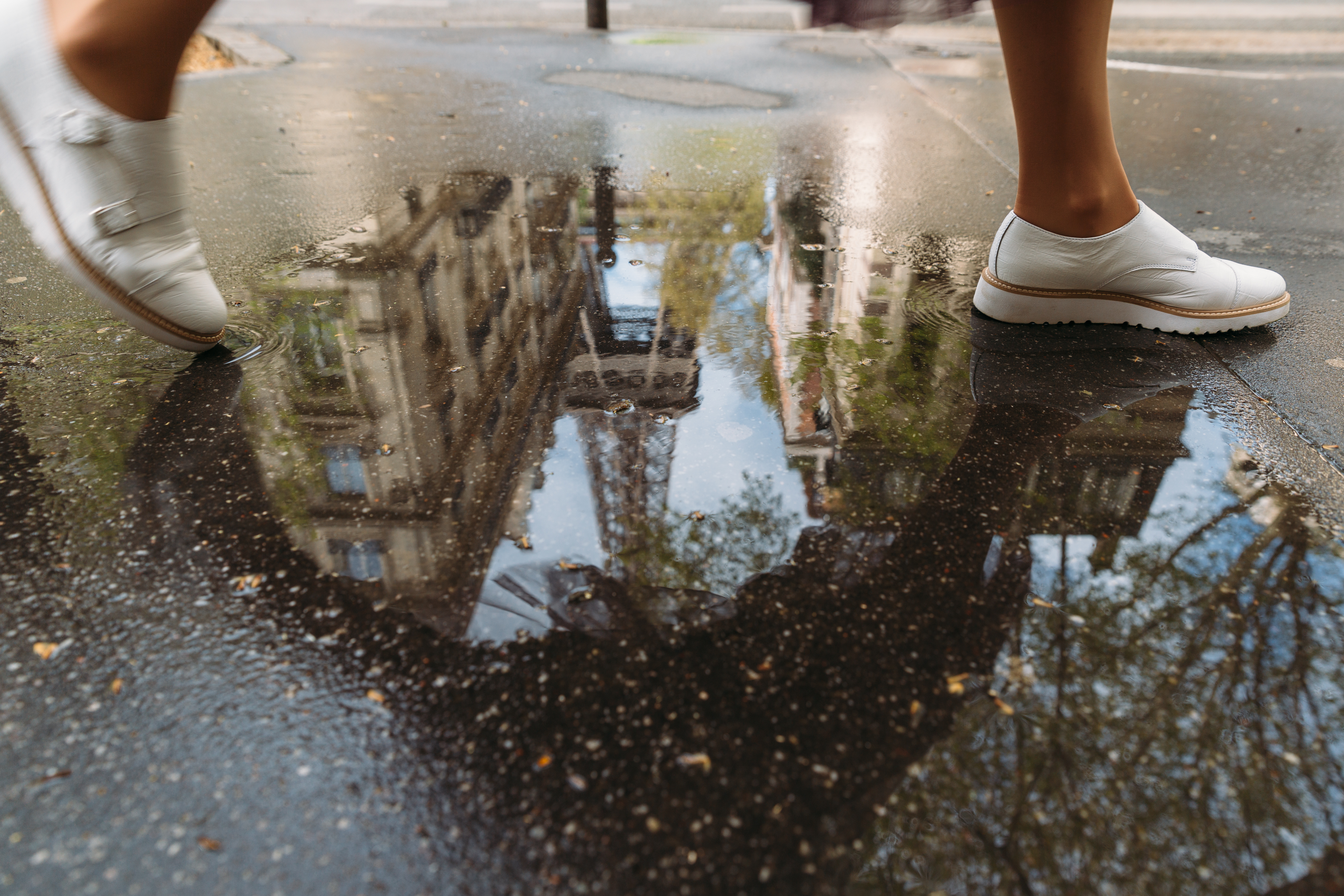 a woman walks through a puddle reflecting the Eiffel Tower on a trip to Paris, France