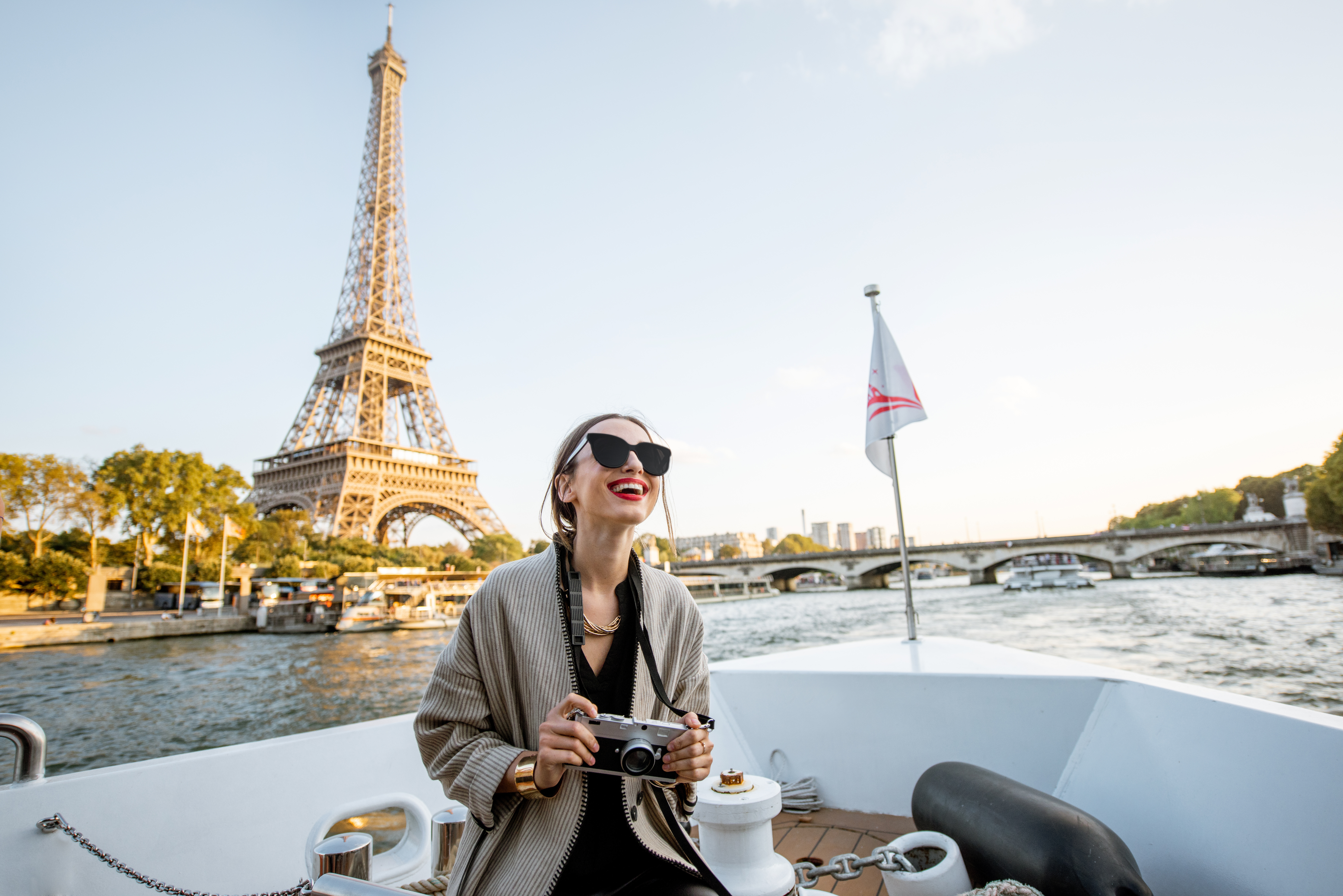 woman with camera on a river boat alongside landmarks