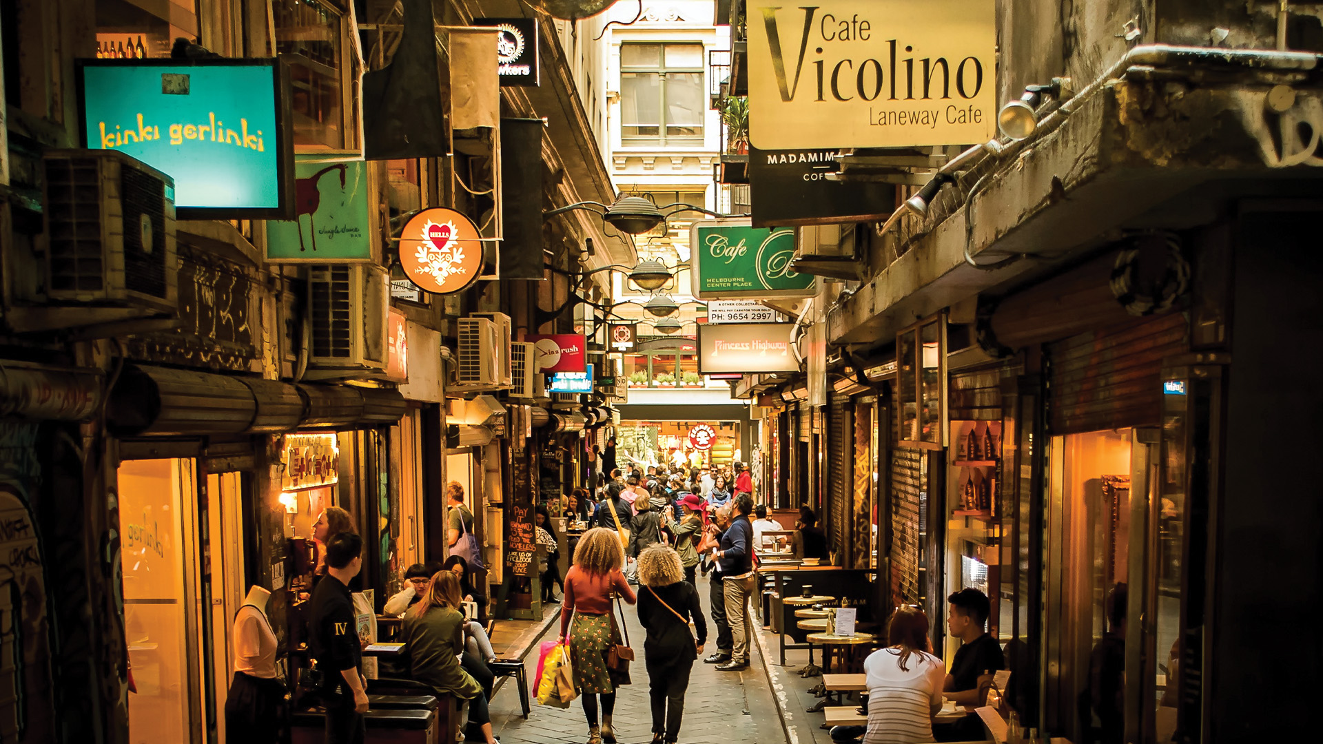 people walking down a laneway with restaurants