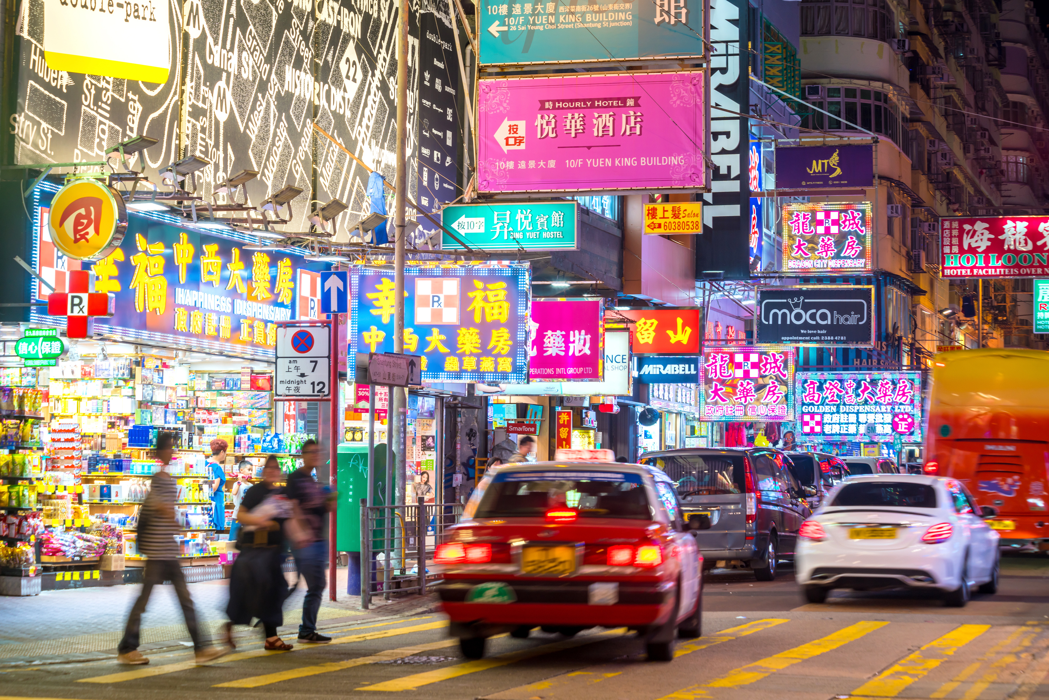 neon signs and cabs on a busy city street in East Asia