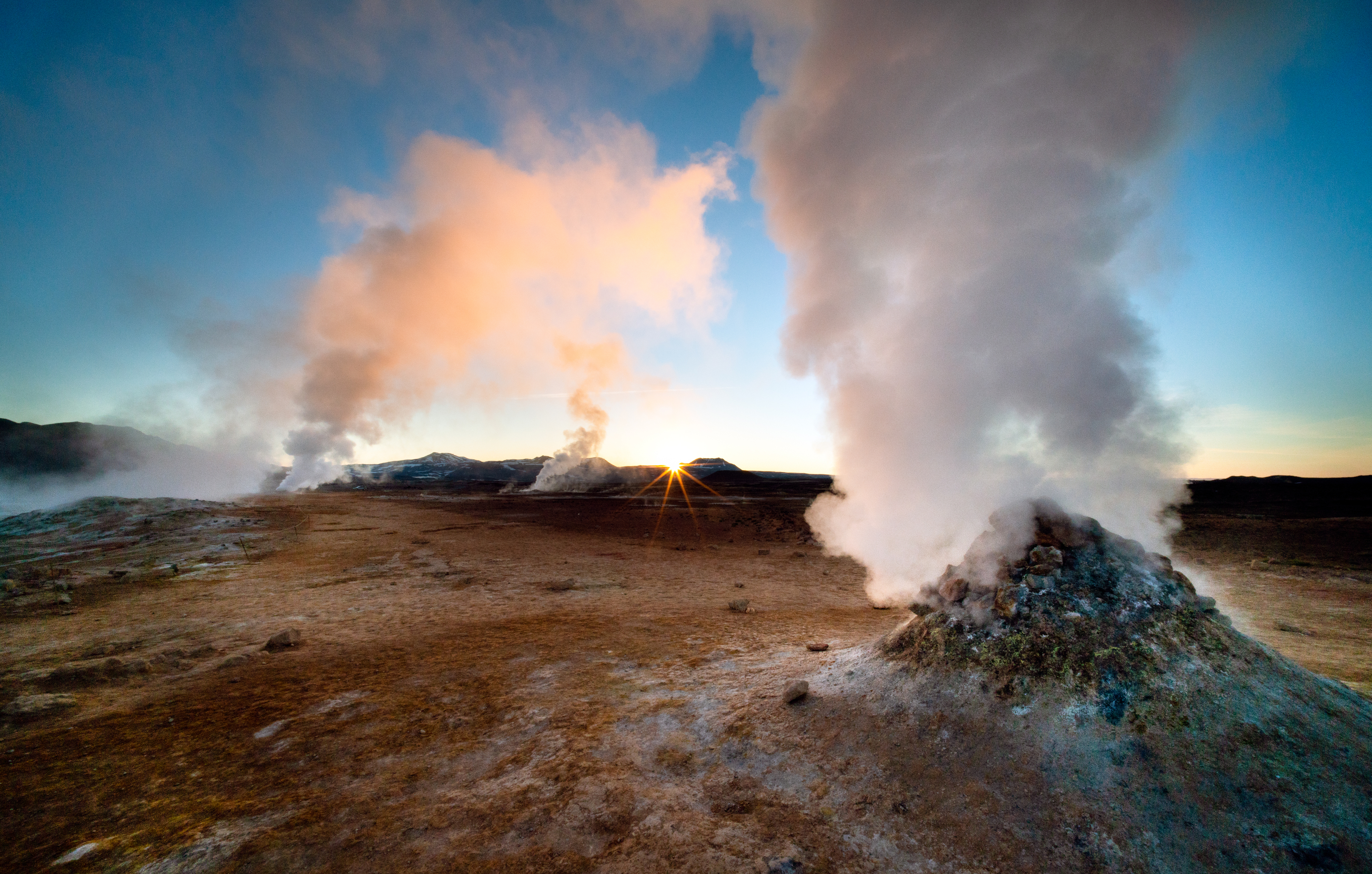 A beautiful dawn in Iceland, a country with many geothermal features including these dramatic fumaroles. Shot with a wide angle lens for dramatic effect and a small aperture to create a sunstar where the sun is just peaking over the horizon. The scenery in Iceland is spectacular and it is becoming a popular tourist destination.