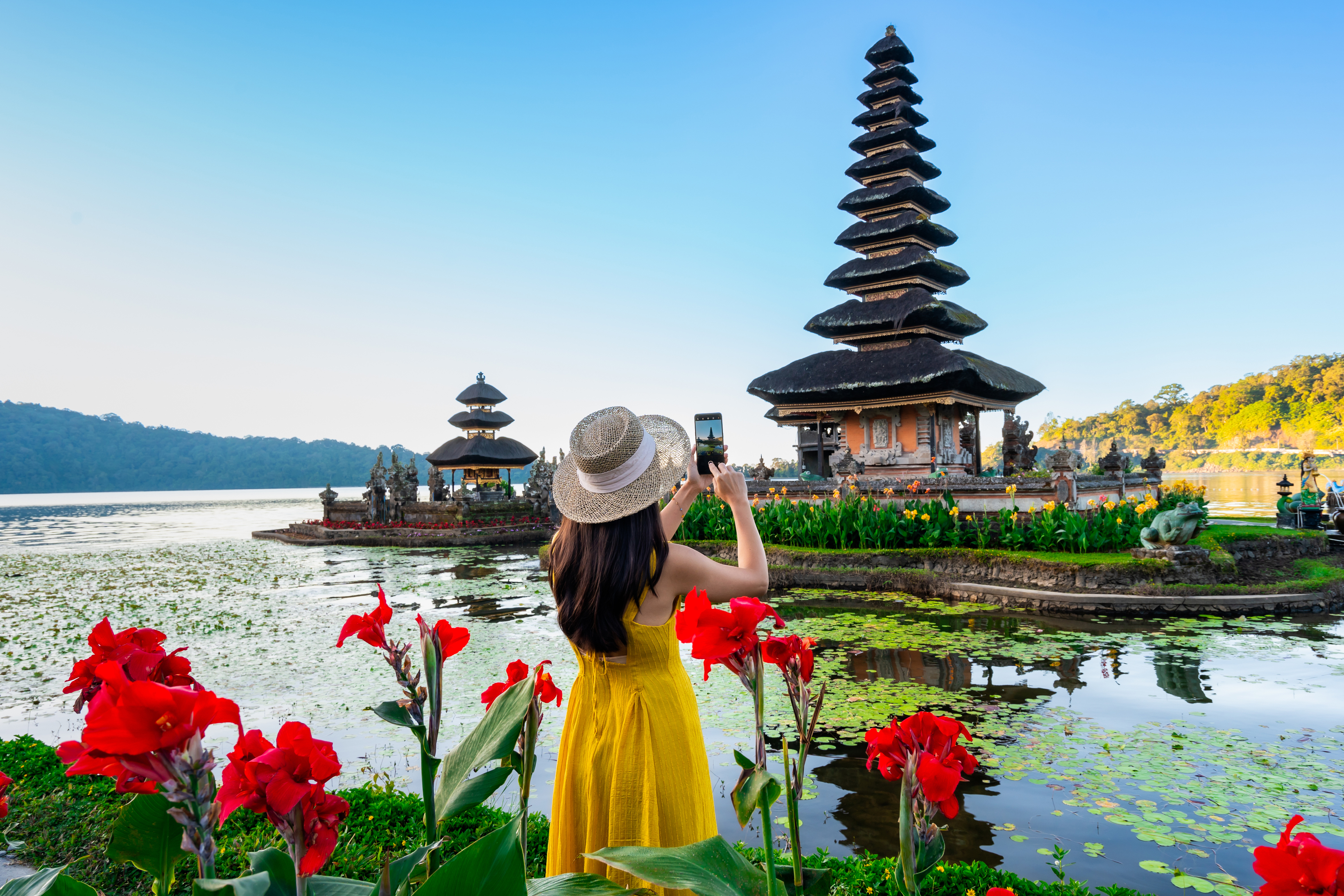 Young woman tourist relaxing and enjoying the beautiful view at Ulun Danu Beratan temple in Bali, Indonesia