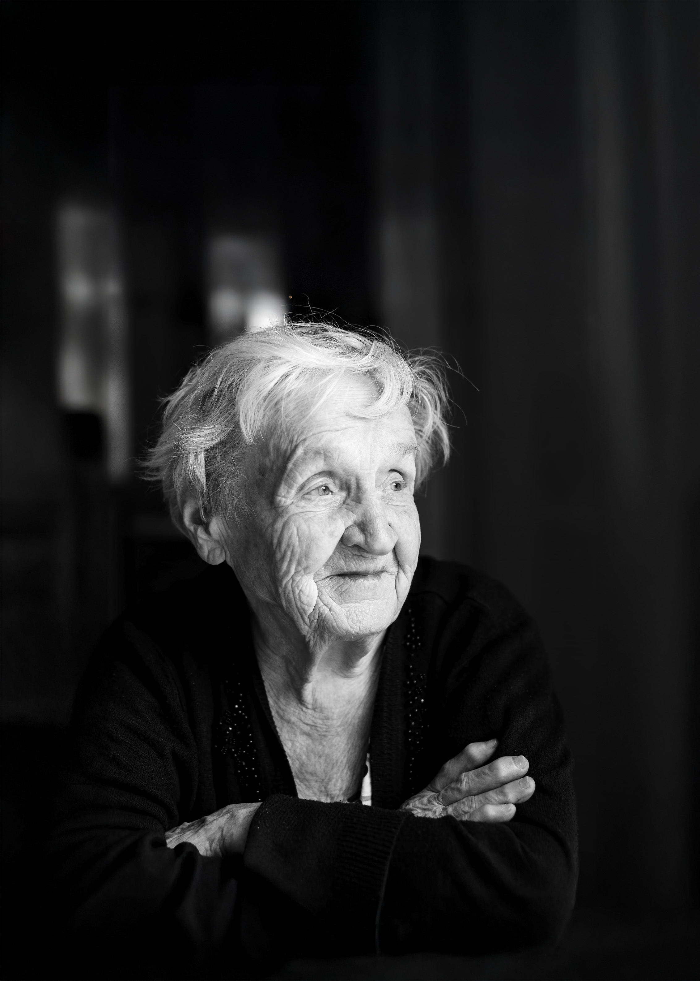 An old woman in black and white looking to the right of the frame.