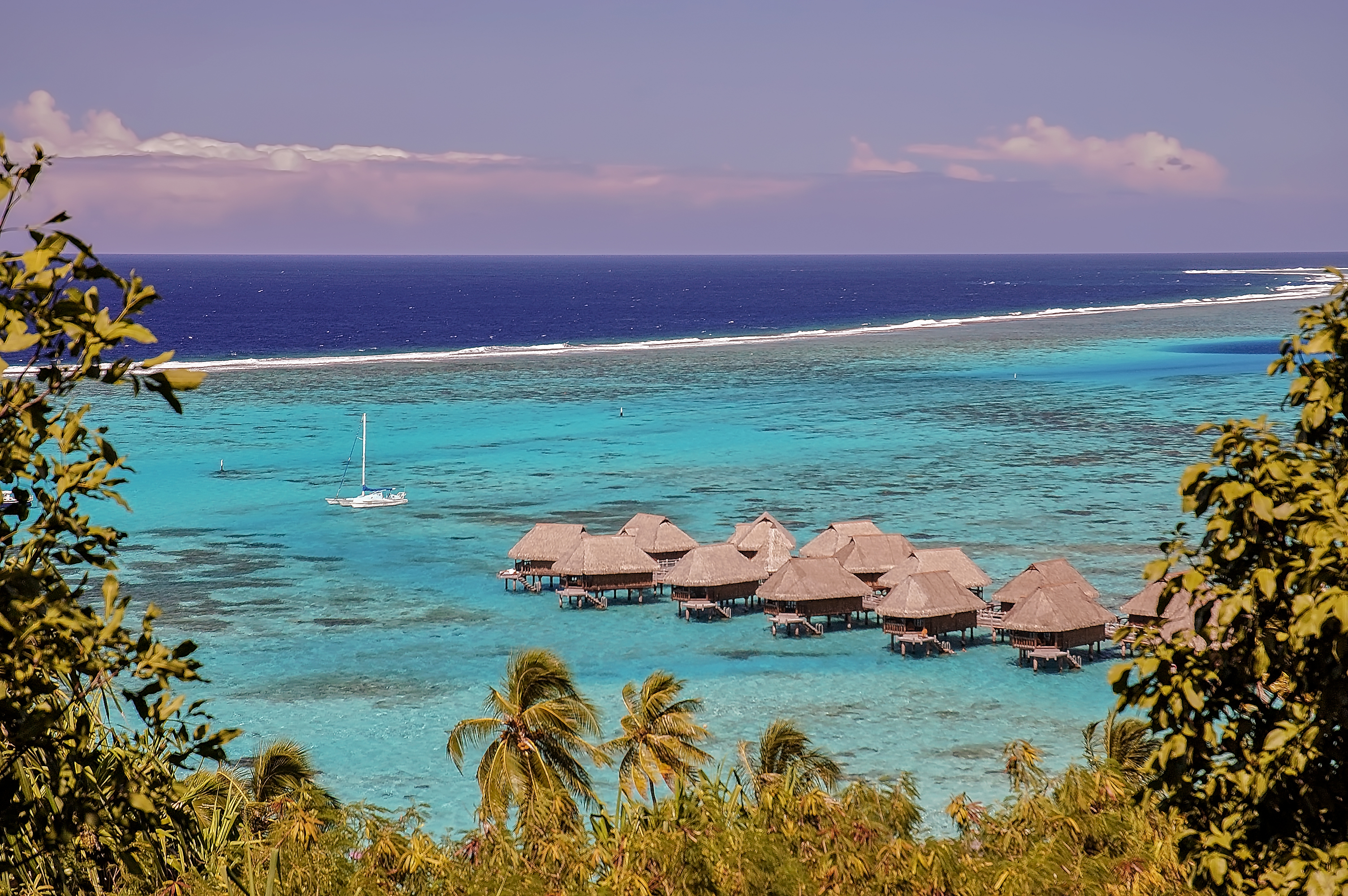 View of the coral reef surrounding a French Polynesia island, and the ocean of two colors: bungalows on the turquoise colored water of the shallow lagoon and blue color for the deep ocean.