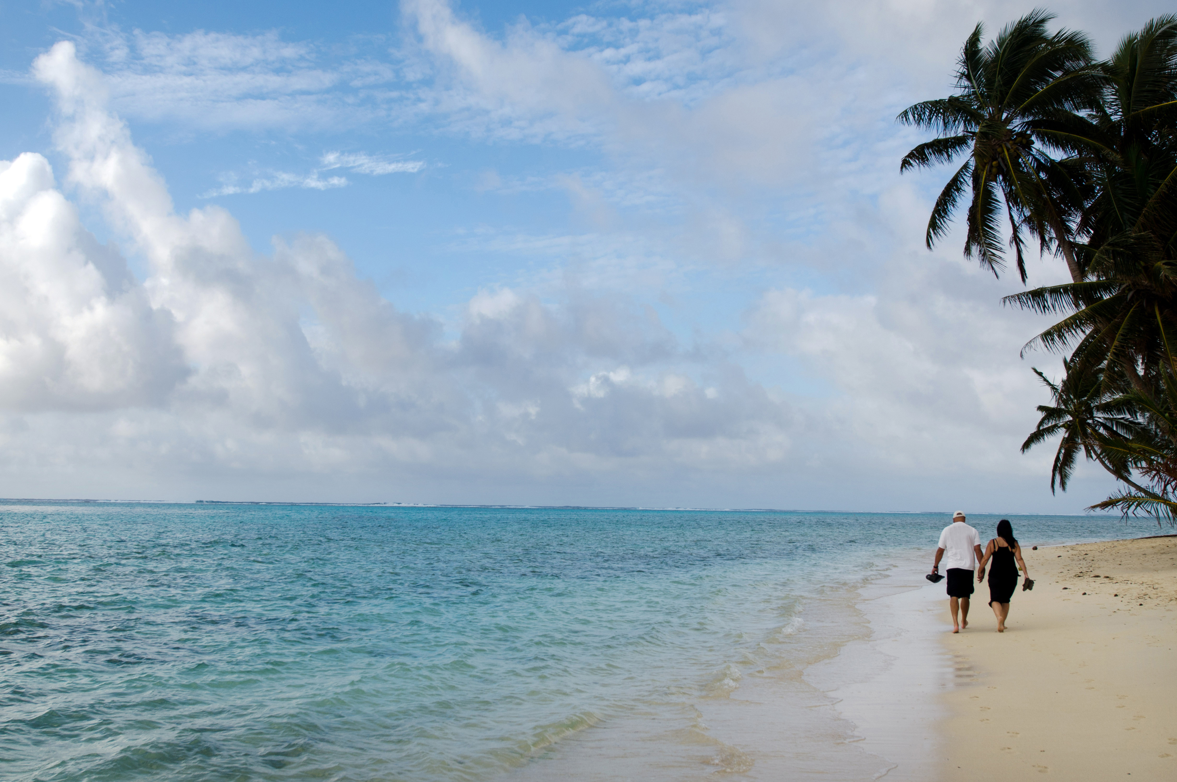 Pacific Islander couple walks on the beach at Muri Lagoon in Rarotonga Cook Islands during sunrise.