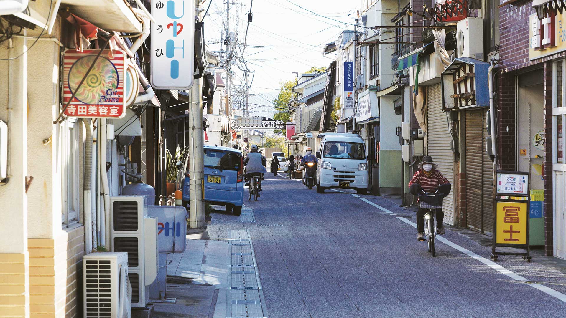 view of street in Japan with cars and shops on either side