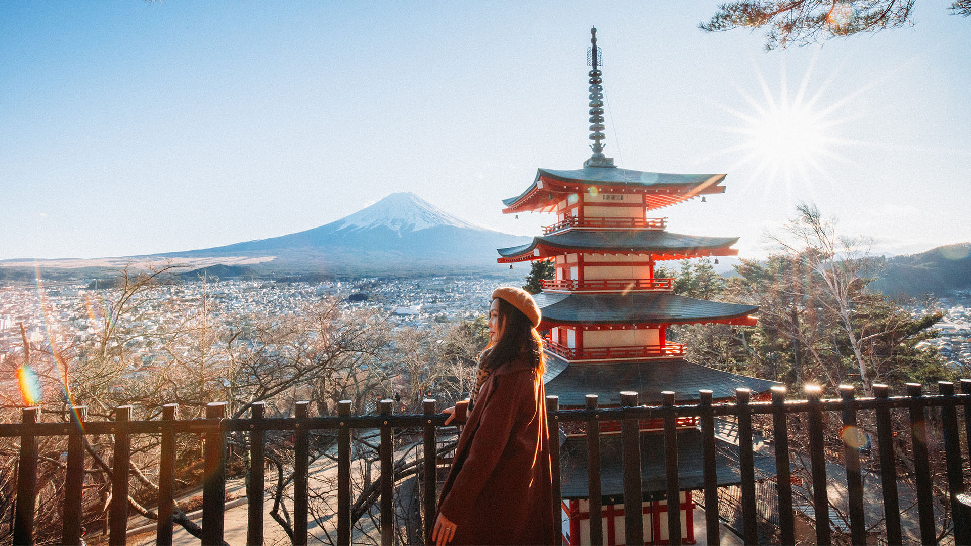 A woman standing in front of Mount Fuji and a Japanese pagoda during the autumn season