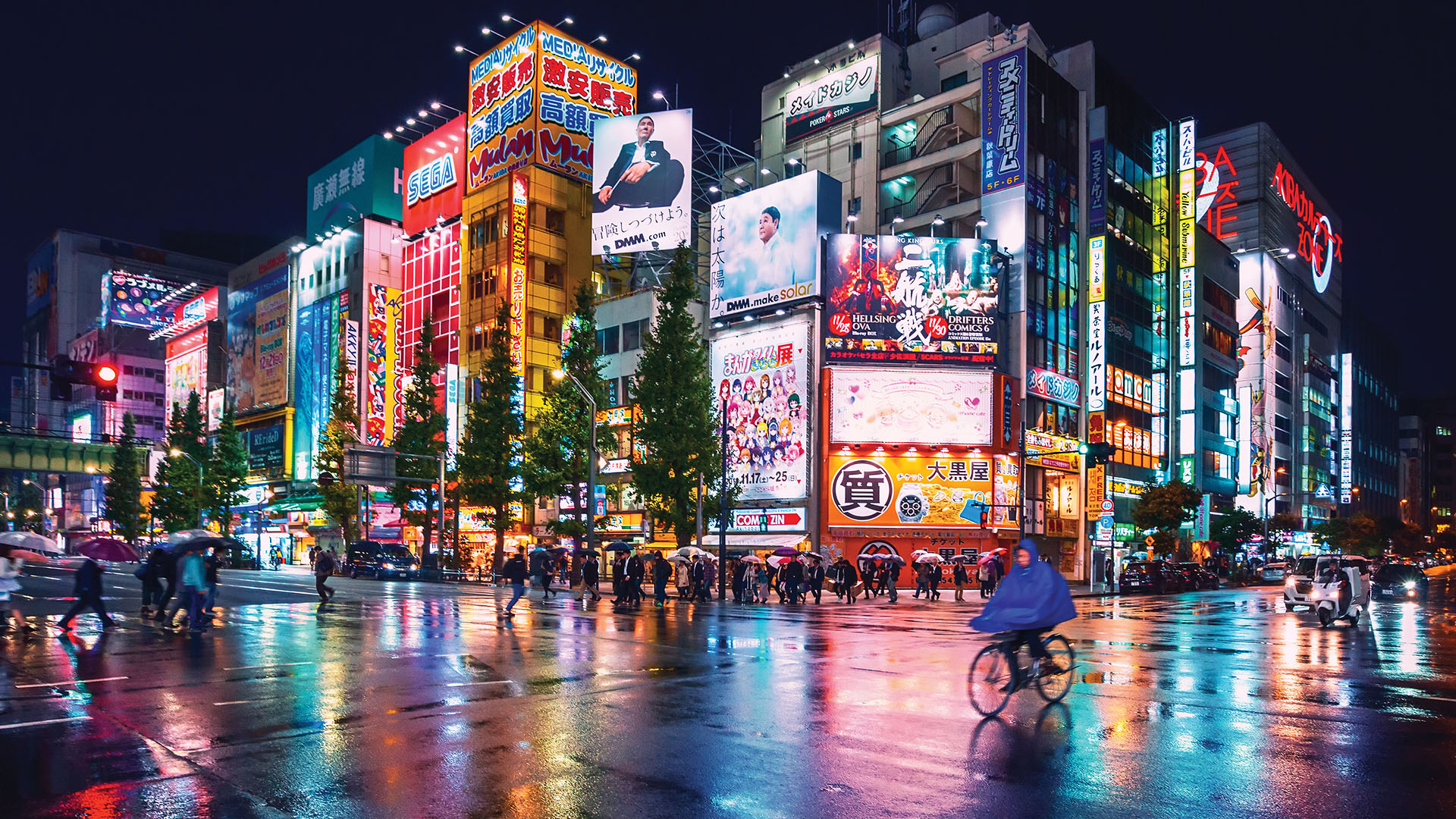 Pedestrians walking and biking in front of a brightly lit and colourful intersection in Tokyo