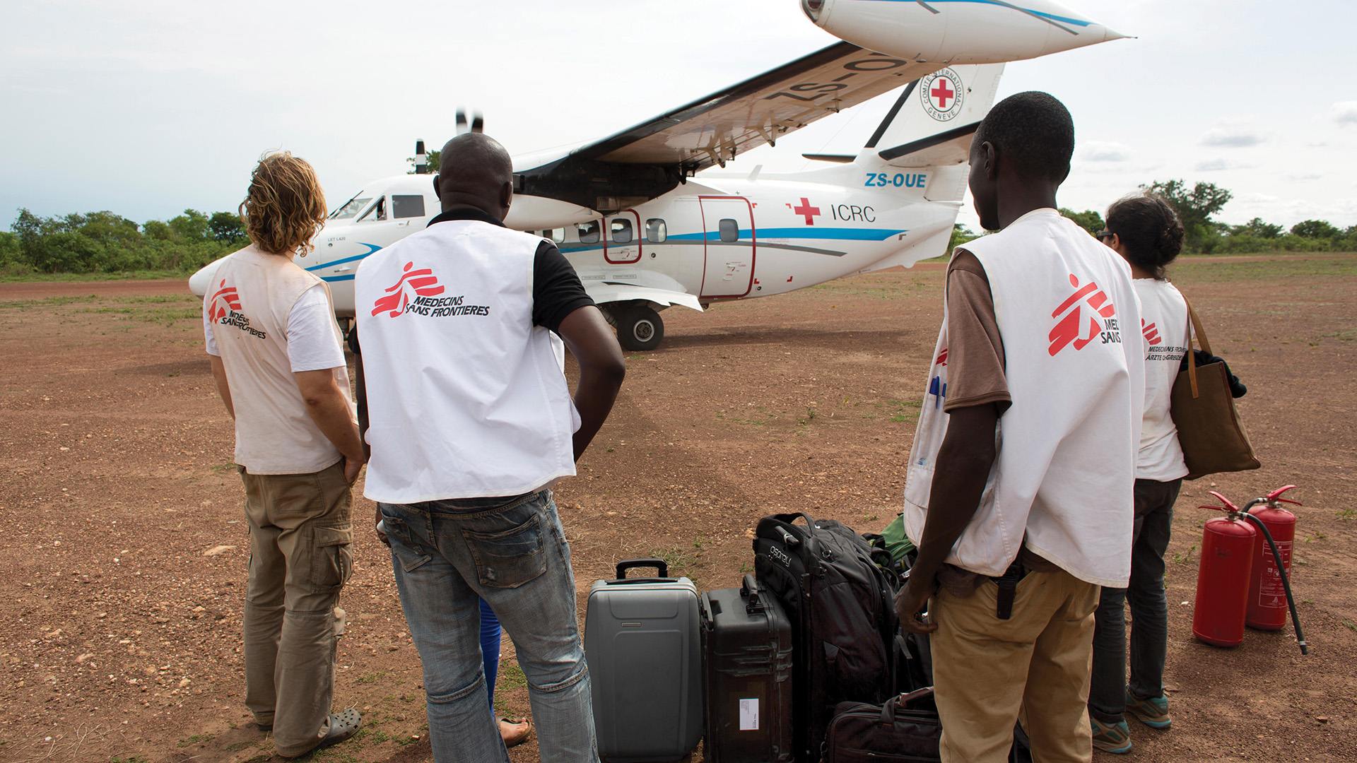Doctors for MSF with luggage standing in front of a small plane