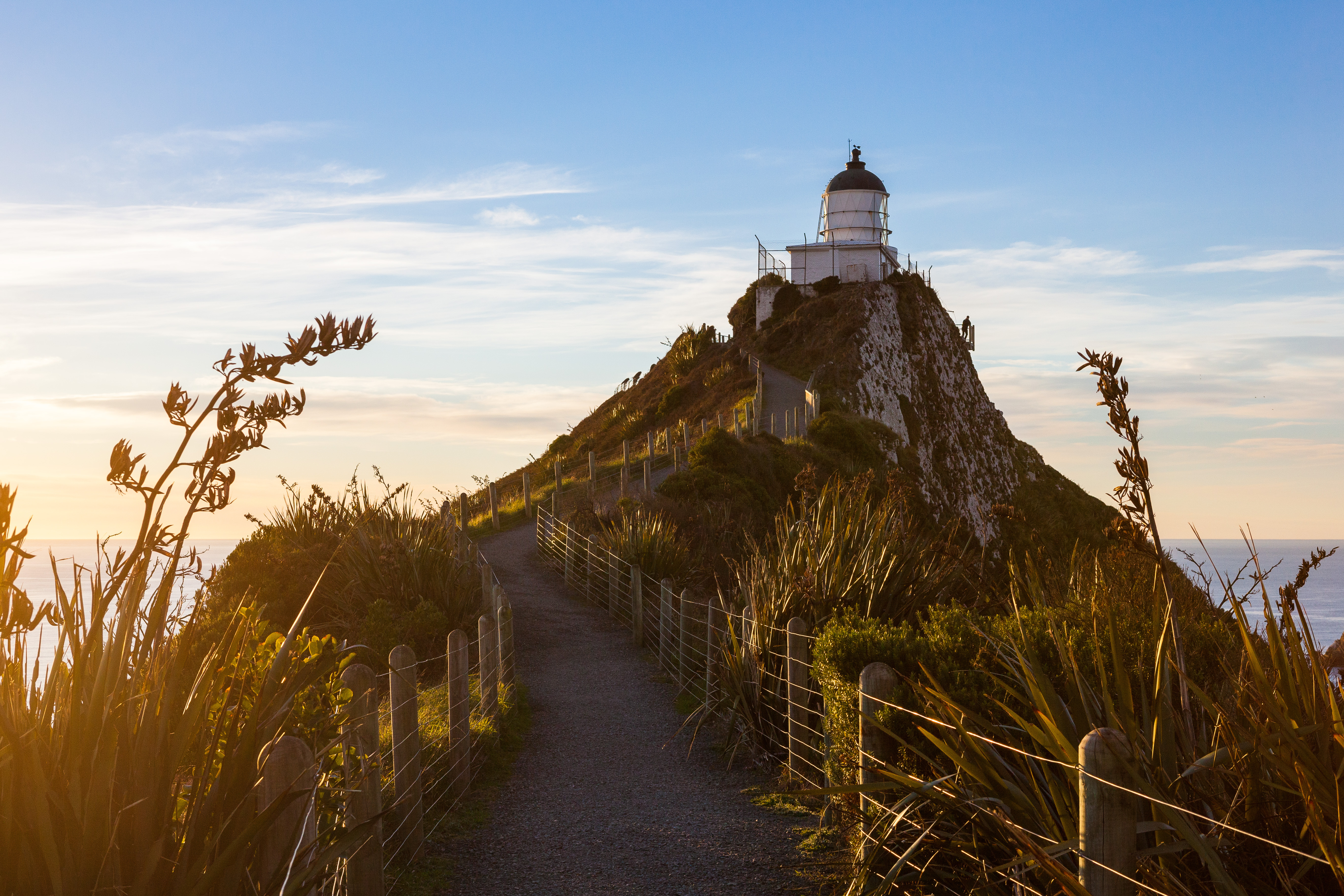 hillside path leading to a lighthouse overlooking the ocean
