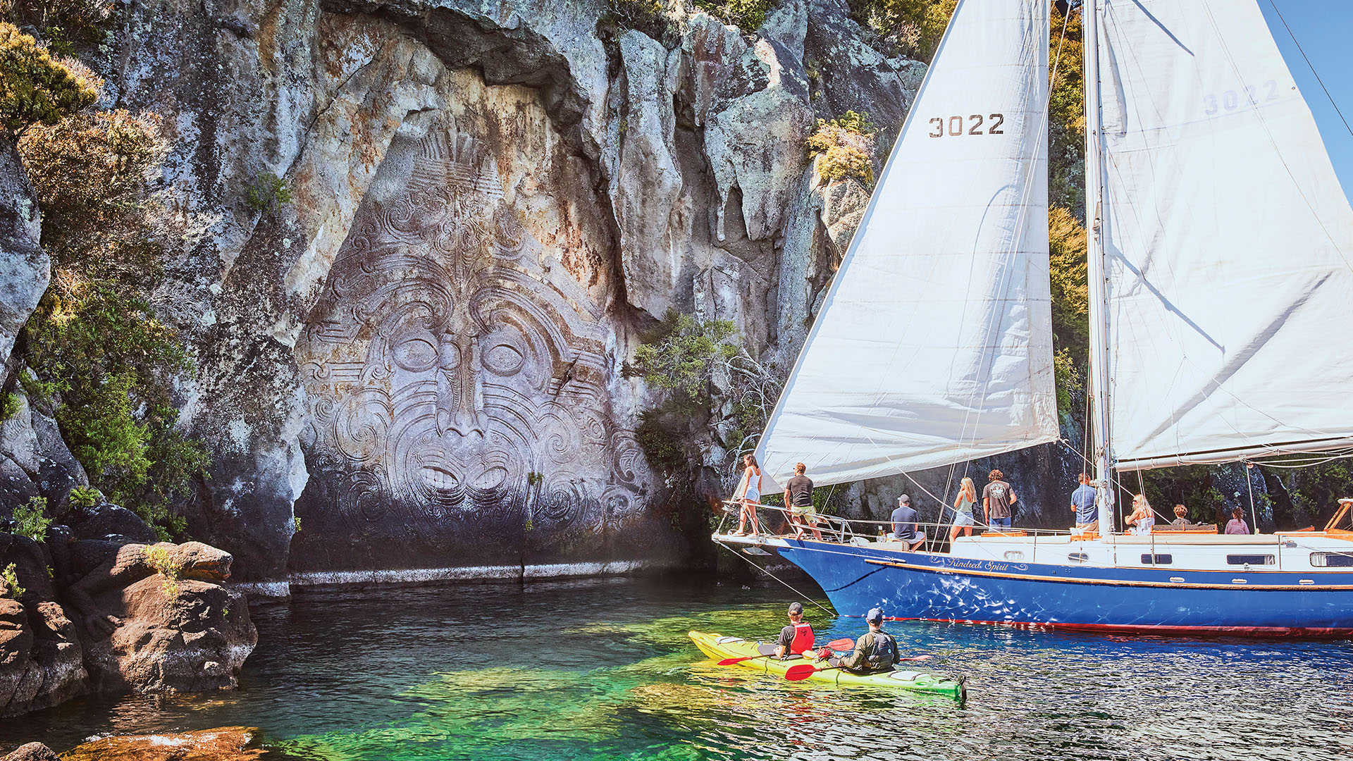 A kayak and sailboat in front of Maori carvings near Lake Taupo, New Zealand