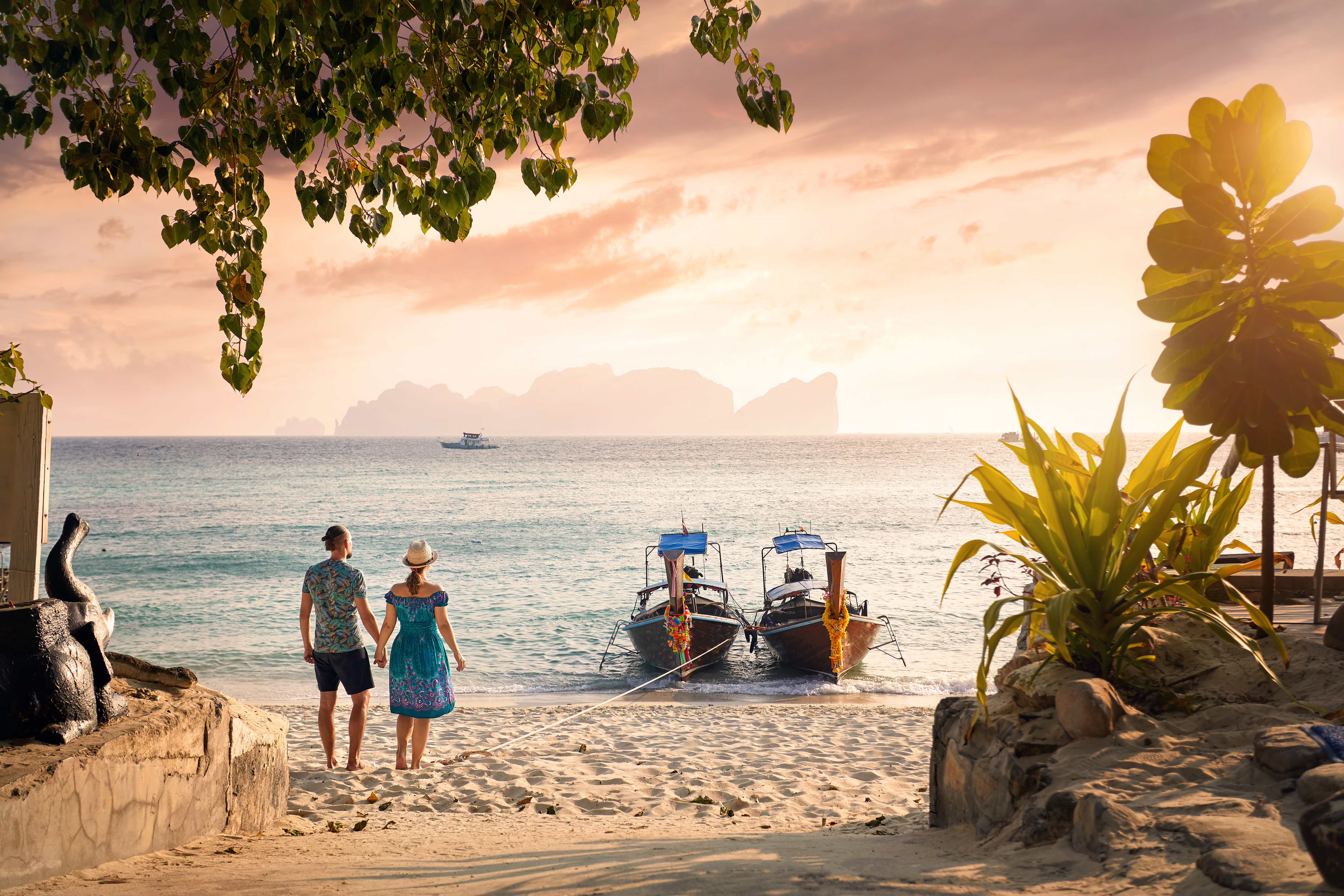 Happy couple on the tropical beach of Phi Phi island at sunset in Southern Thailand.