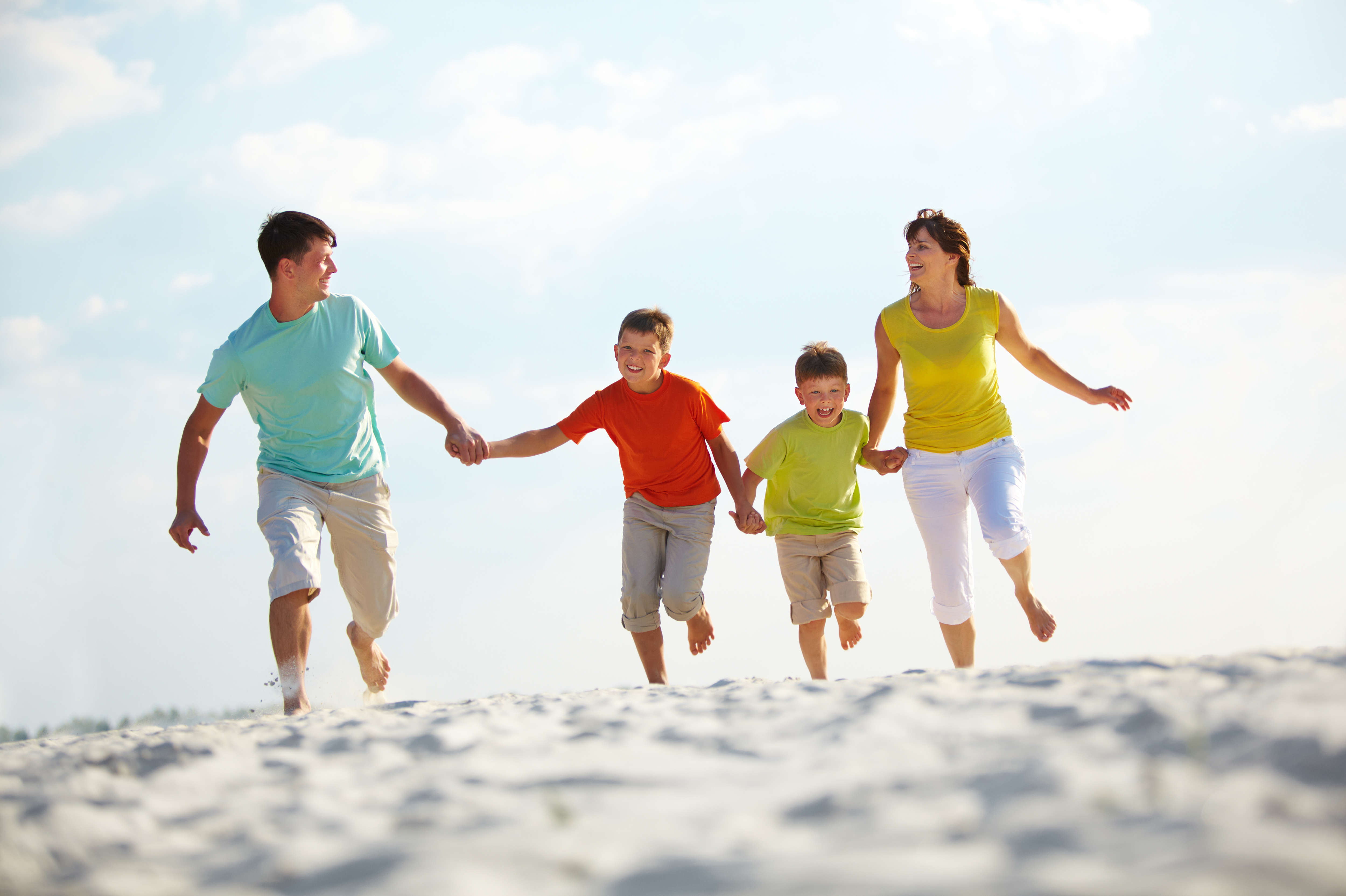 Happy family running down the beach on summer