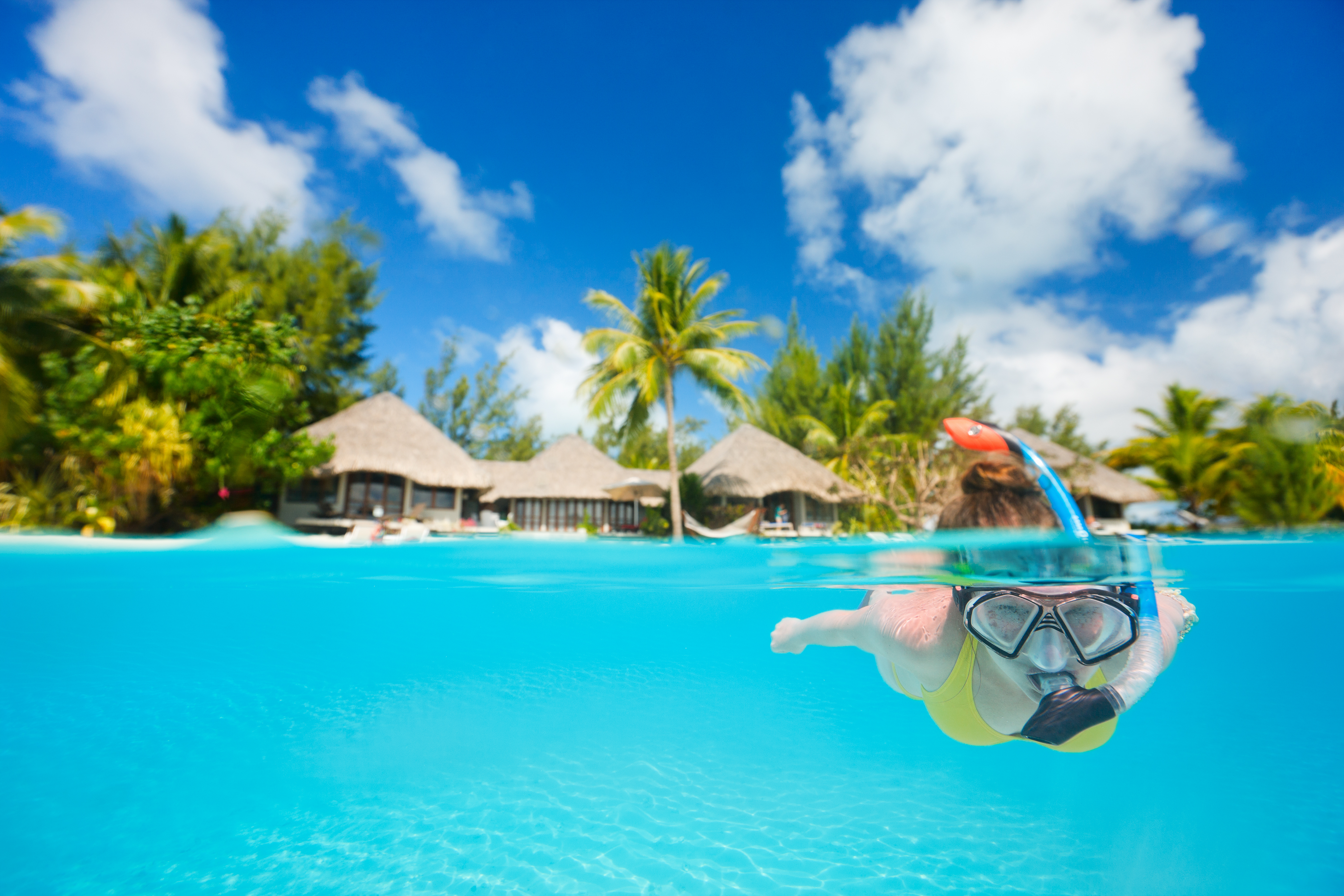 Woman snorkeling in clear tropical waters in front of exotic island, Bora Bora, Tahiti (French Polynesia)