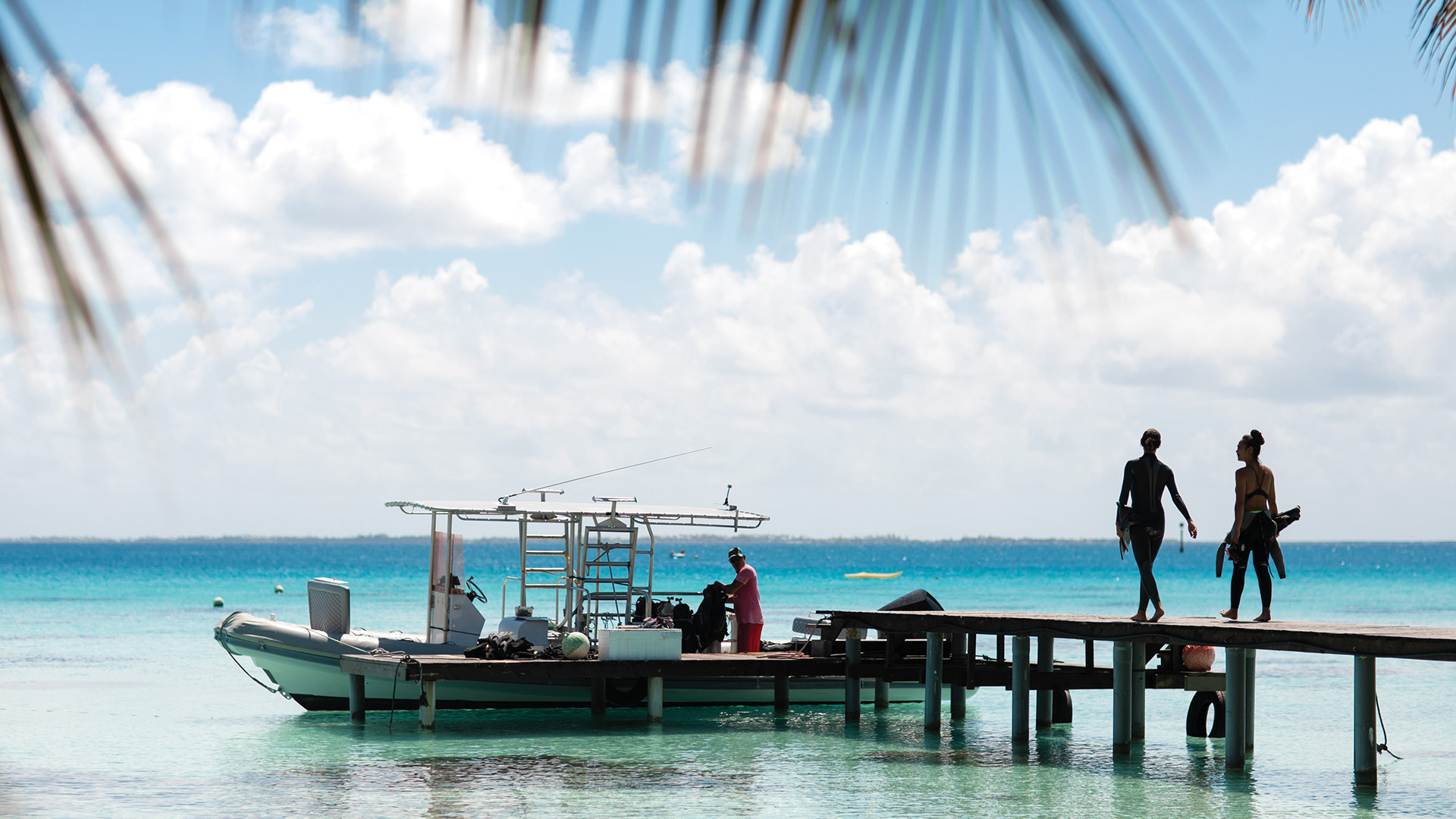 Two people with snorkeling gear boarding a docked motorboat