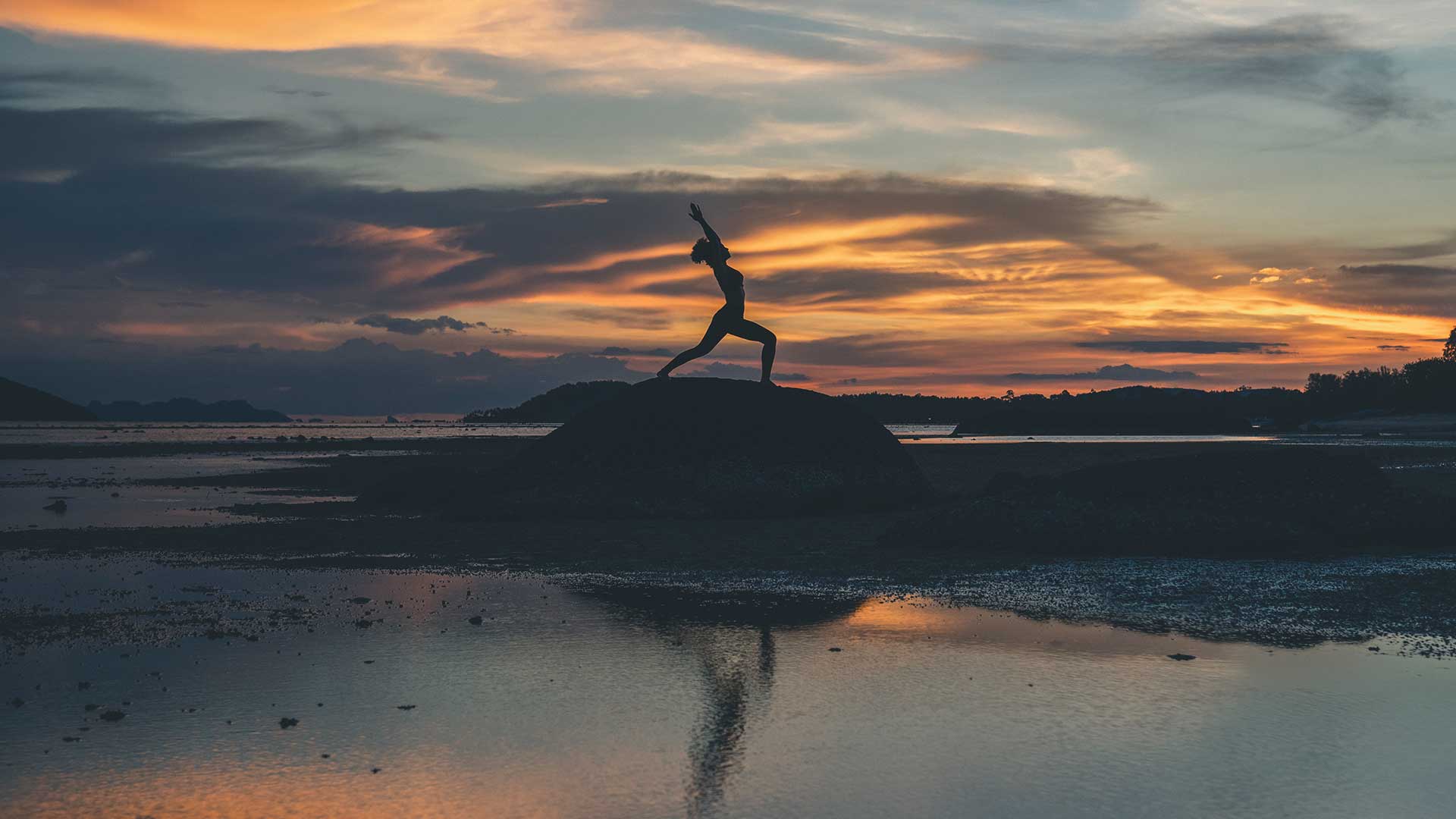 woman doing yoga against sunset