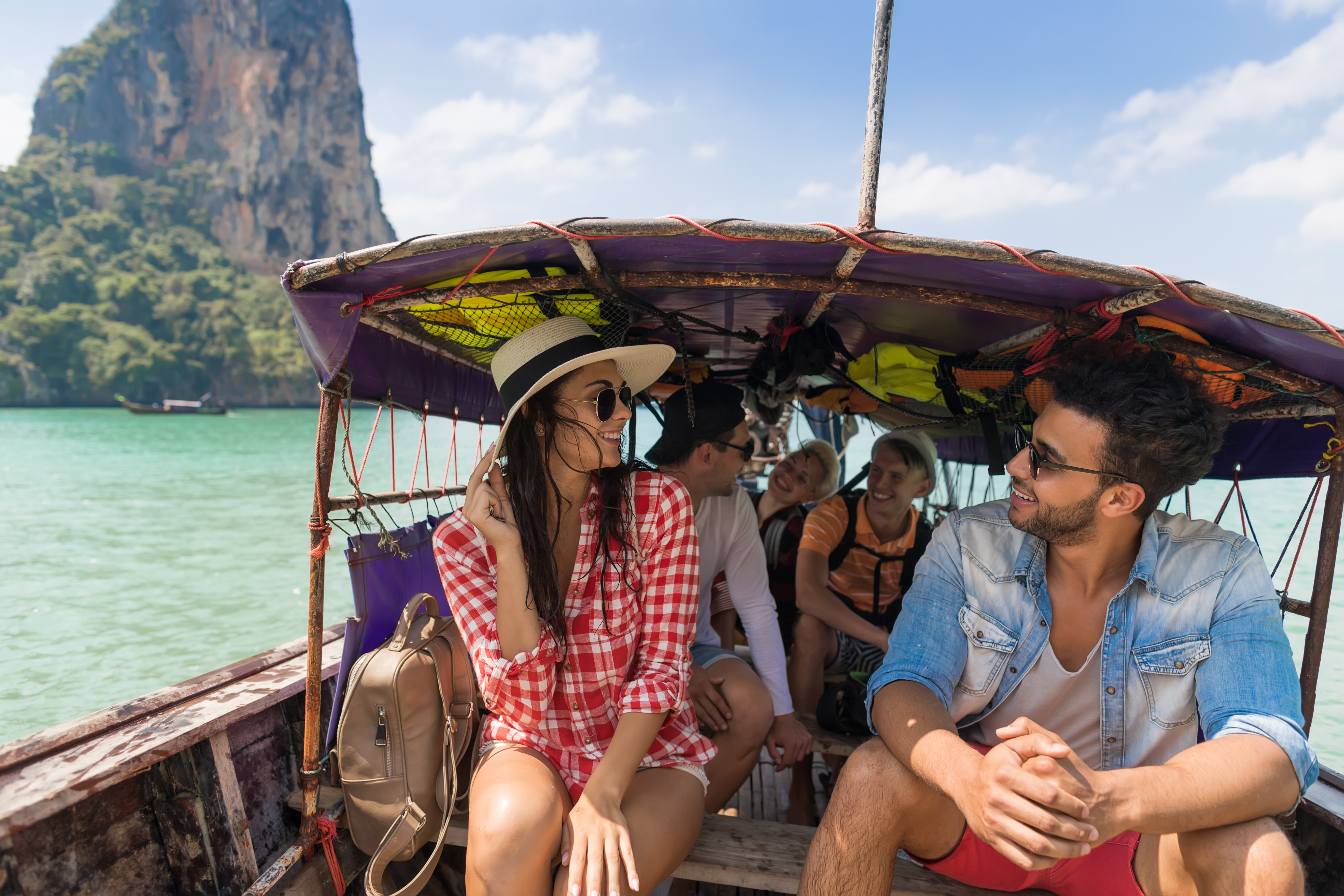 people sharing a traditional boat on the ocean with limestone islands in background