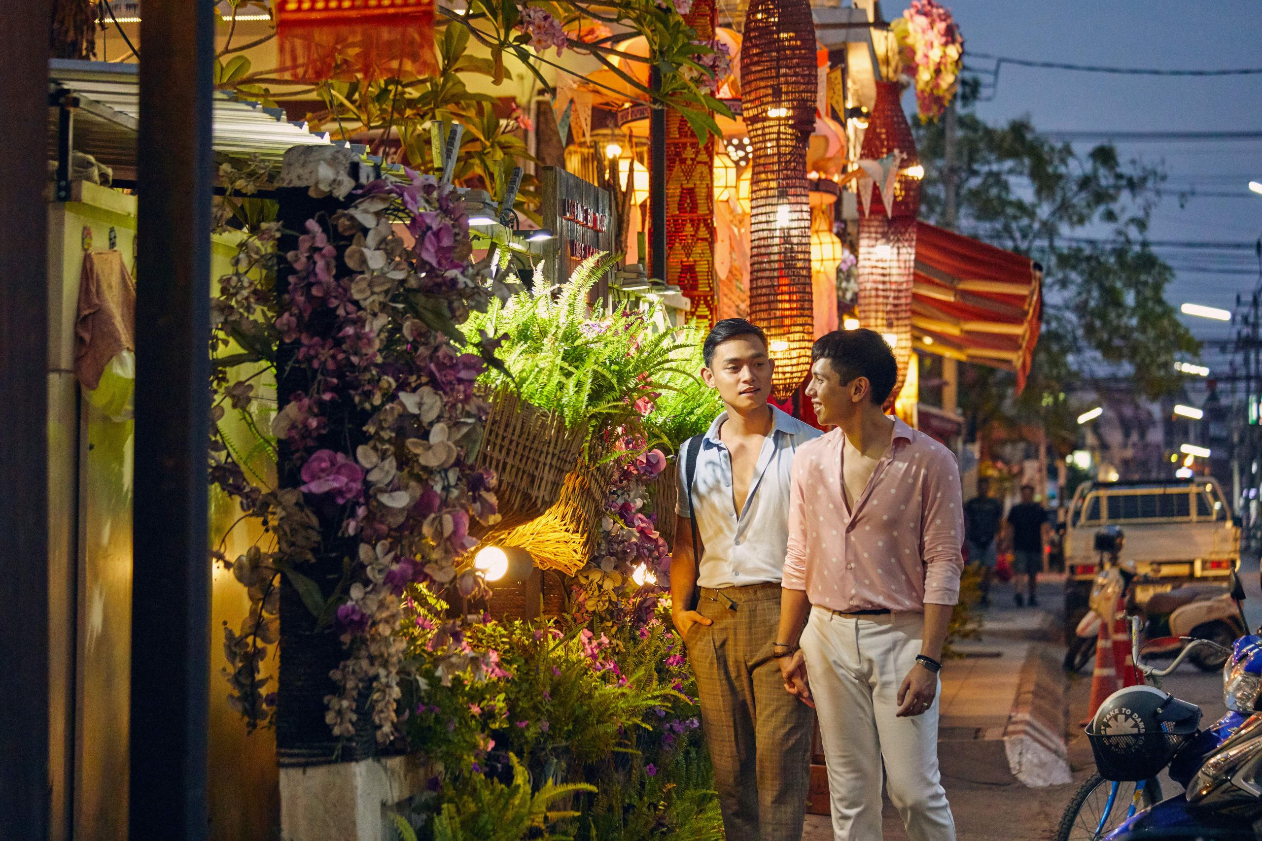 two men walking down a colourful street at night