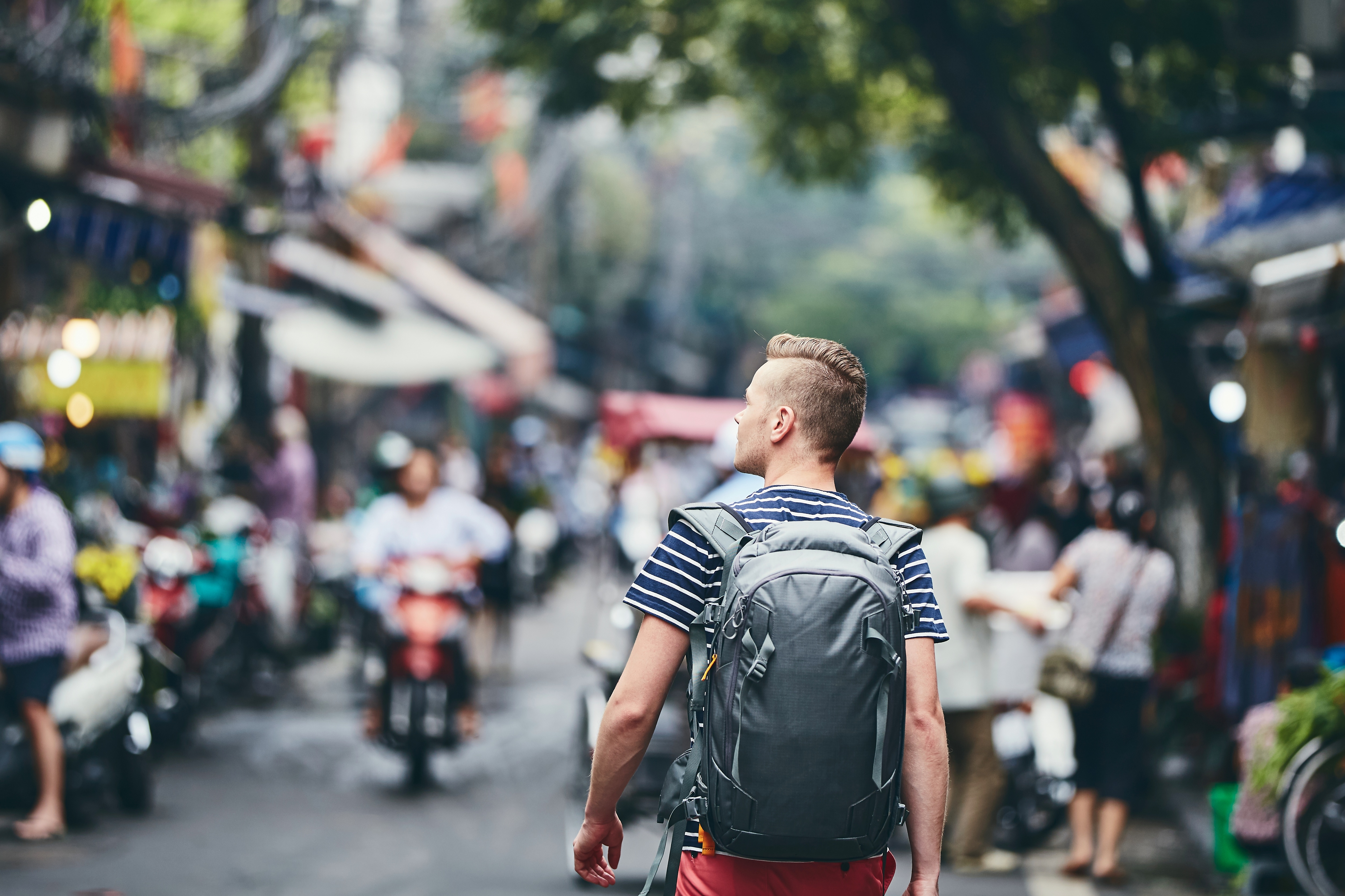 man walking down a street with motorbikes and shops