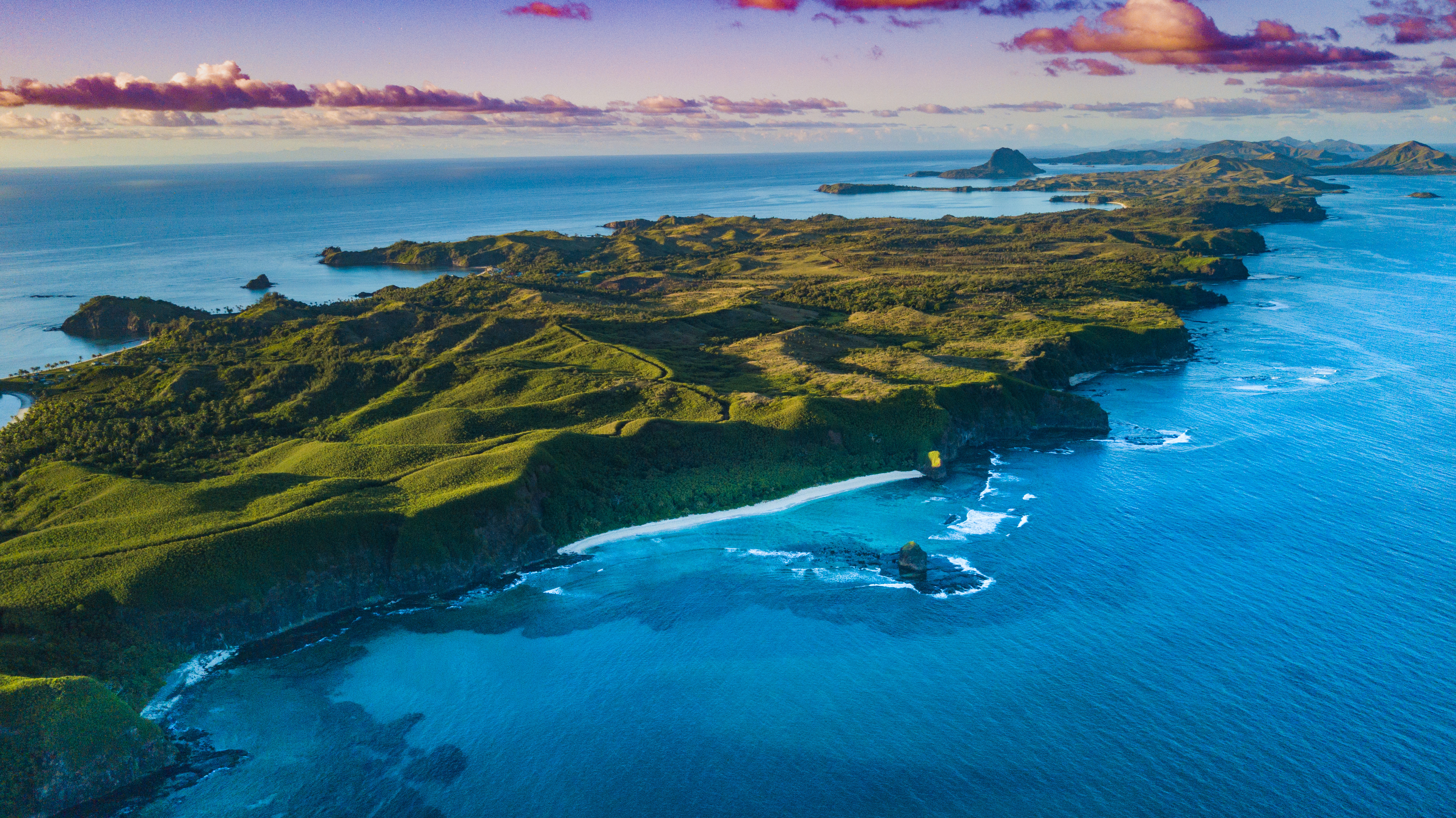 Aerial view of a Fiji island with bright green foliage and sunset sky