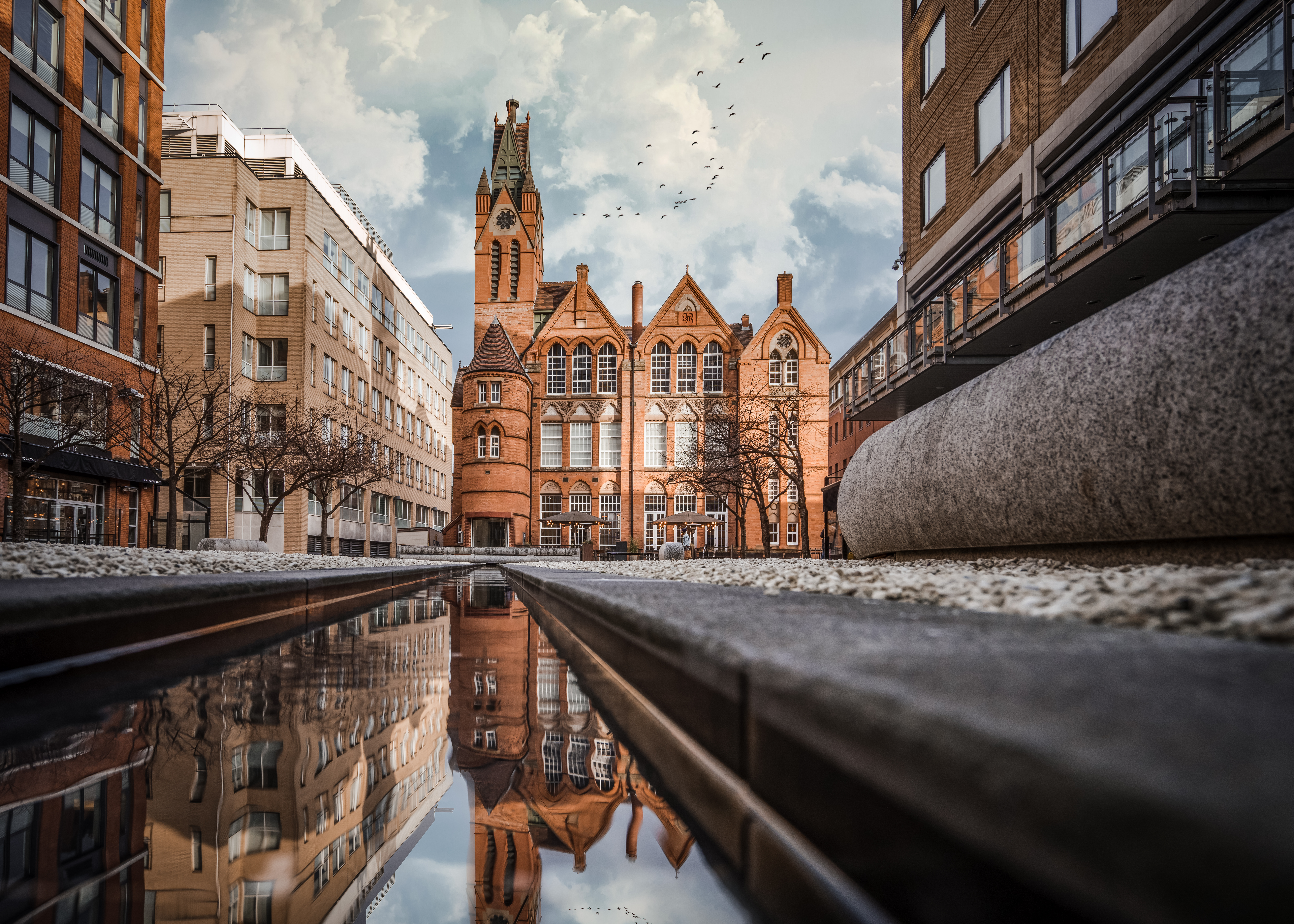 Brindley Place red brick church building reflected in water. West Midlands landmark buildings redevelopment in historic city centre reflection in stream.