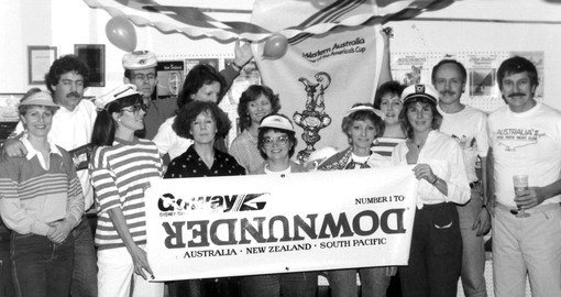 The Goway staff parties in an archival black and white photo of many people holding a sign.