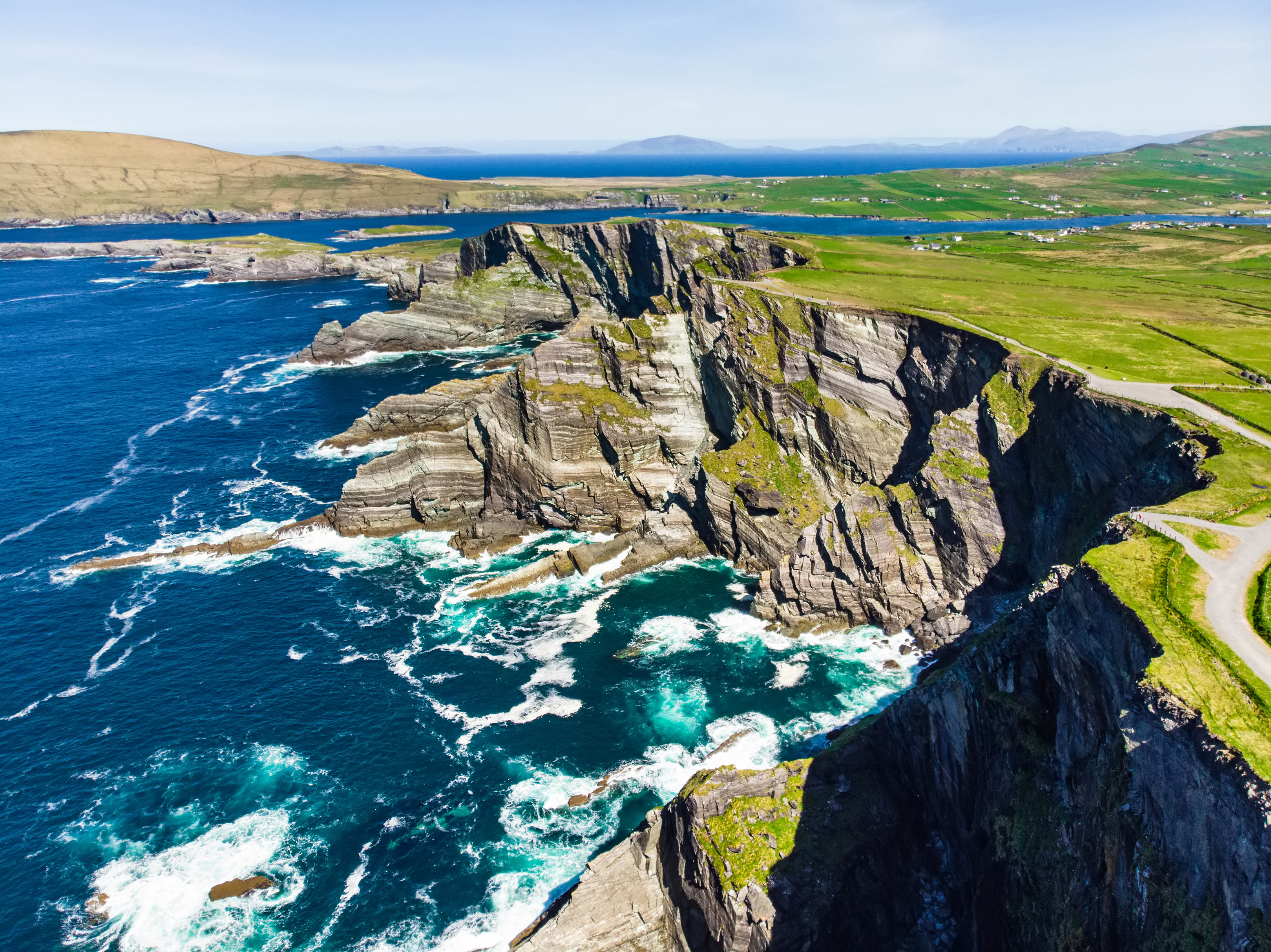 Amazing wave lashed cliffs surrounded be green hills on a sunny day