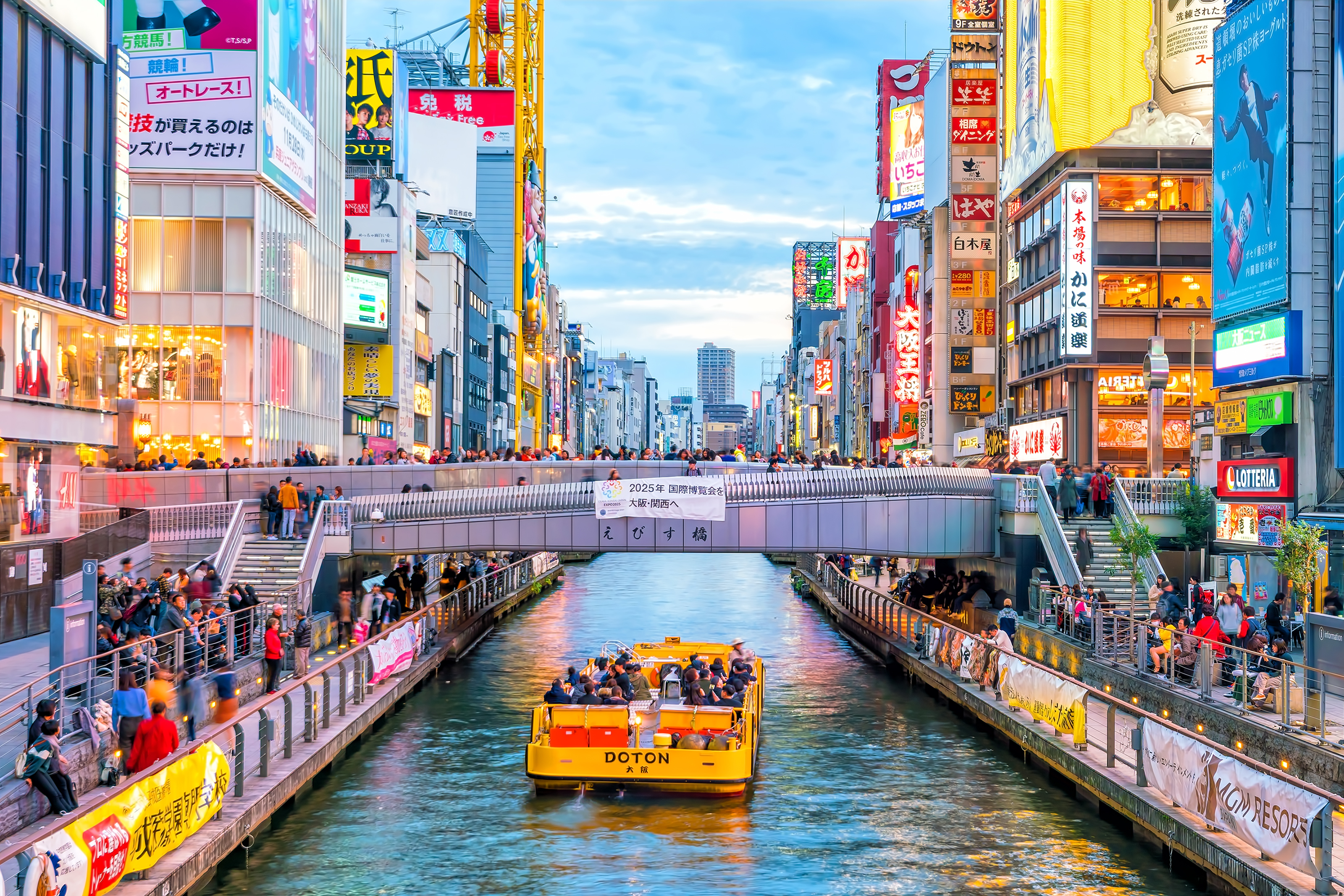 Boat floating down canal on Dotonbori shopping street, a famous destination for traveling and shopping in Osaka