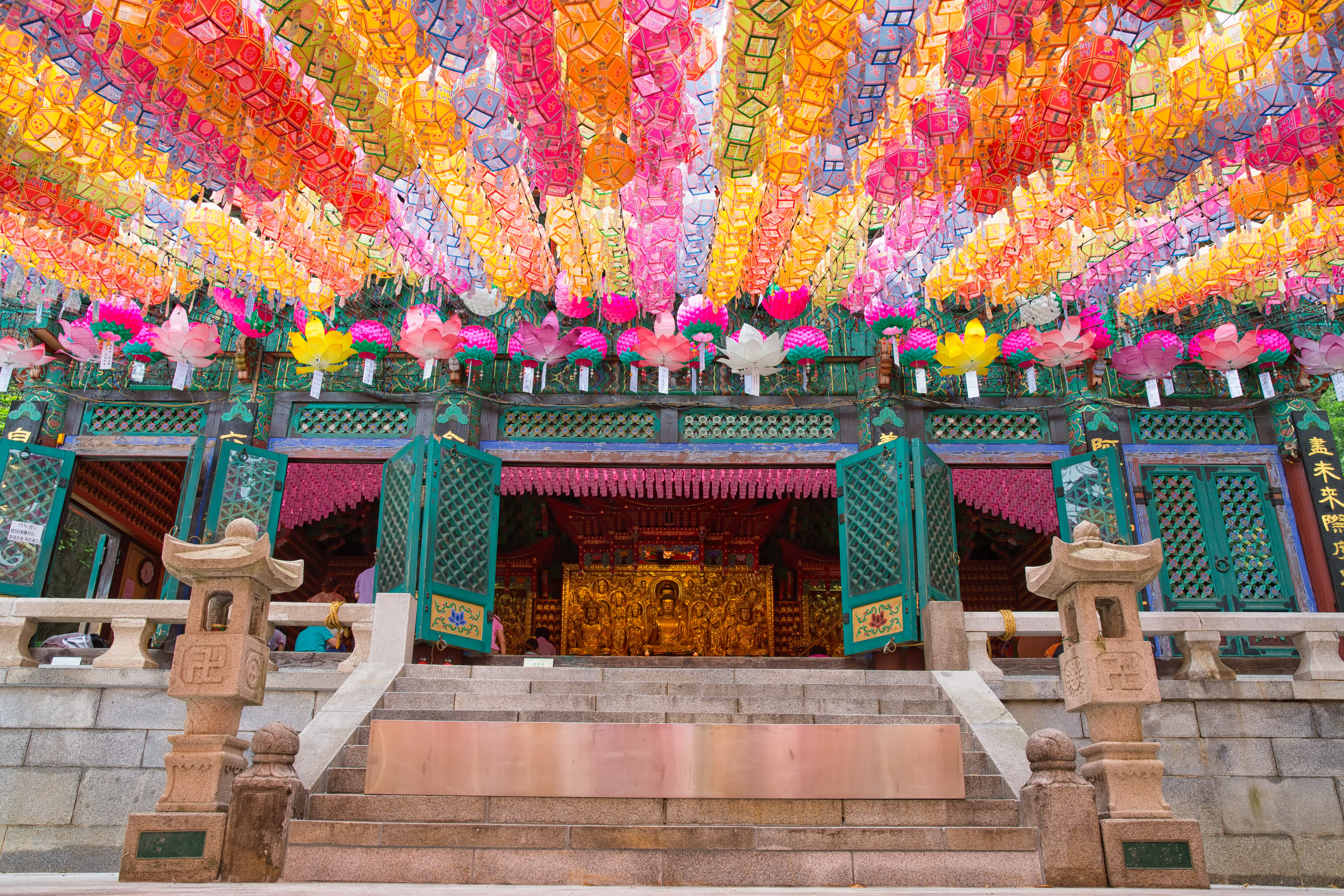 A temple entrance adorned with colorful lanterns hanging from above, creating a vibrant and festive atmosphere.