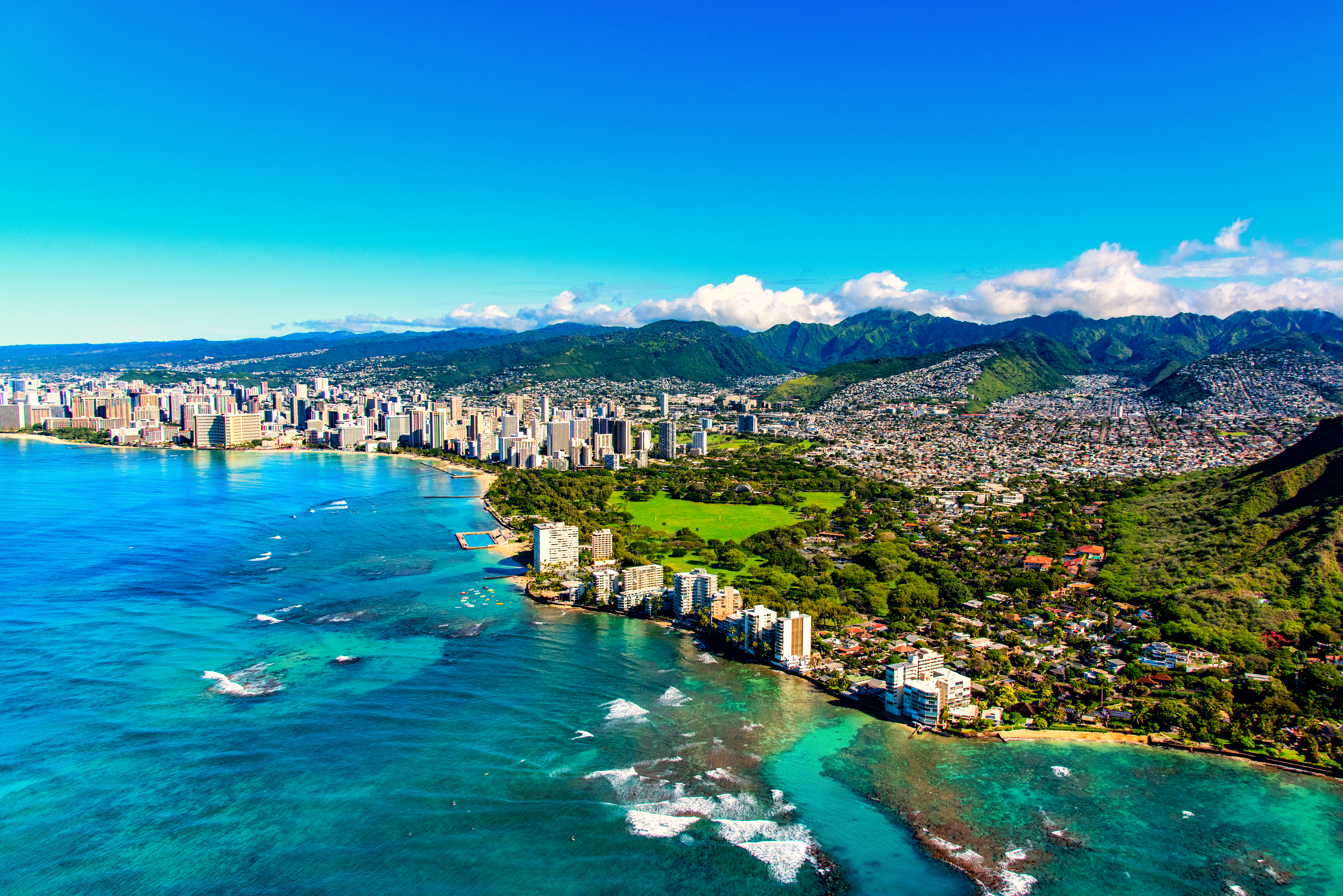 The entire coastline including the base of Diamond Head crater and state park, past the hotel lined Waikiki Beach towards downtown in the distance including the suburban neighborhoods dotting the hills surrounding the city center.