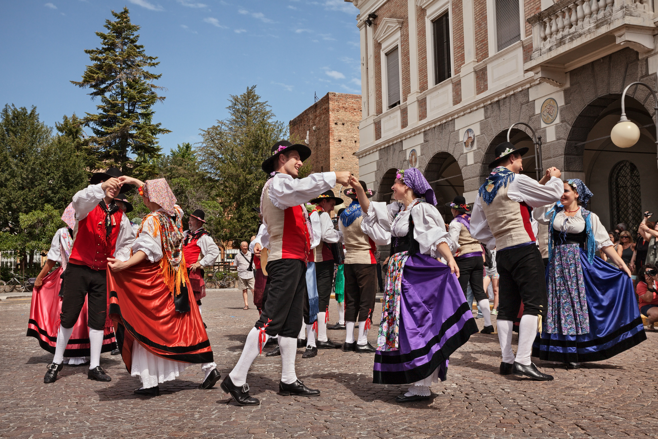 A traditional dance performance with performers in colorful costumes, set in a lively outdoor space.