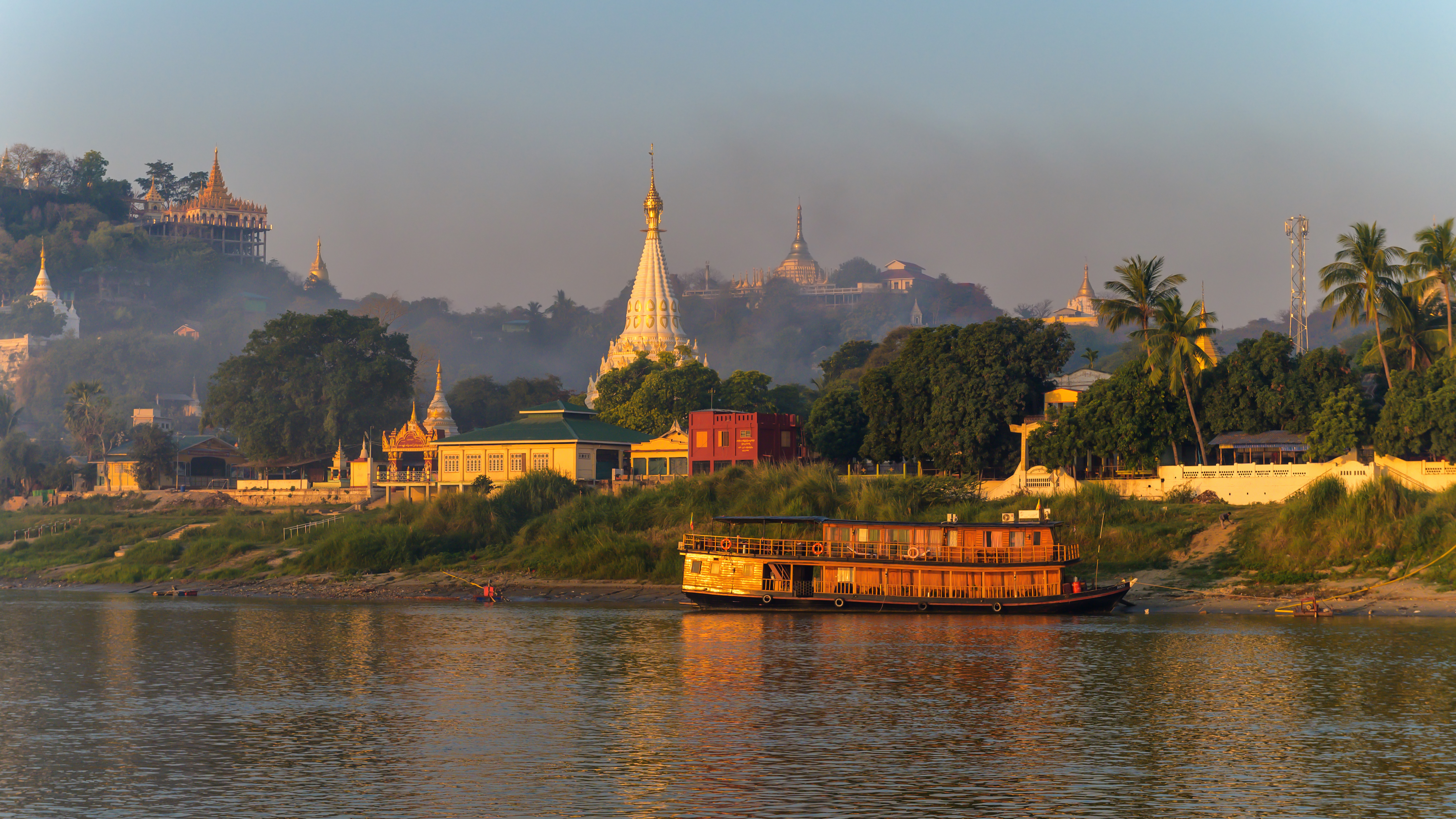 Landscape of Myanmar from the river just after sunrise. Warm colors, lots of pagoda's and a steamboat