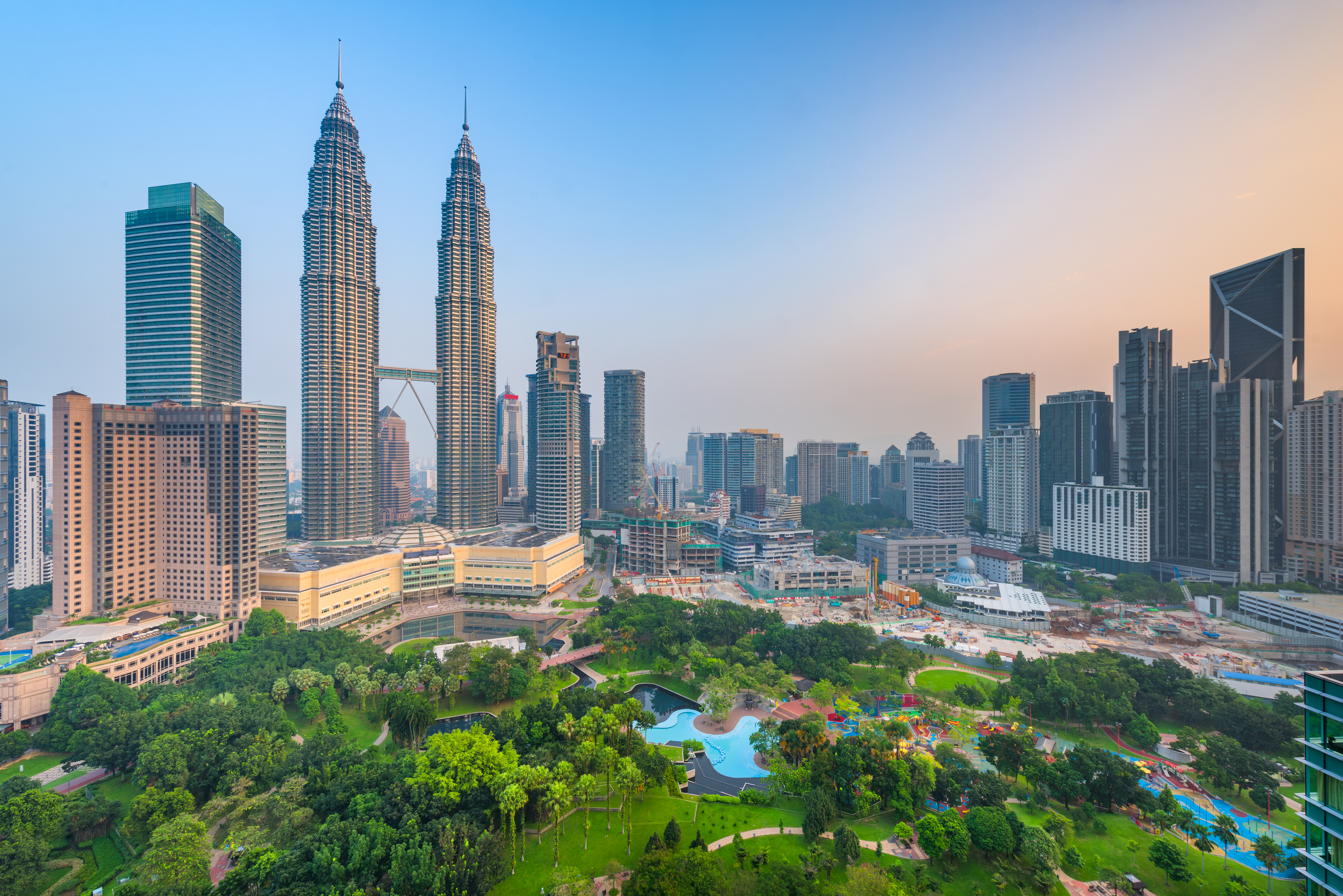 Sunset skyline view of Kuala Lumpur featuring the Petronas Twin Towers, an interlinked pair of 88-storey skyscrapers 