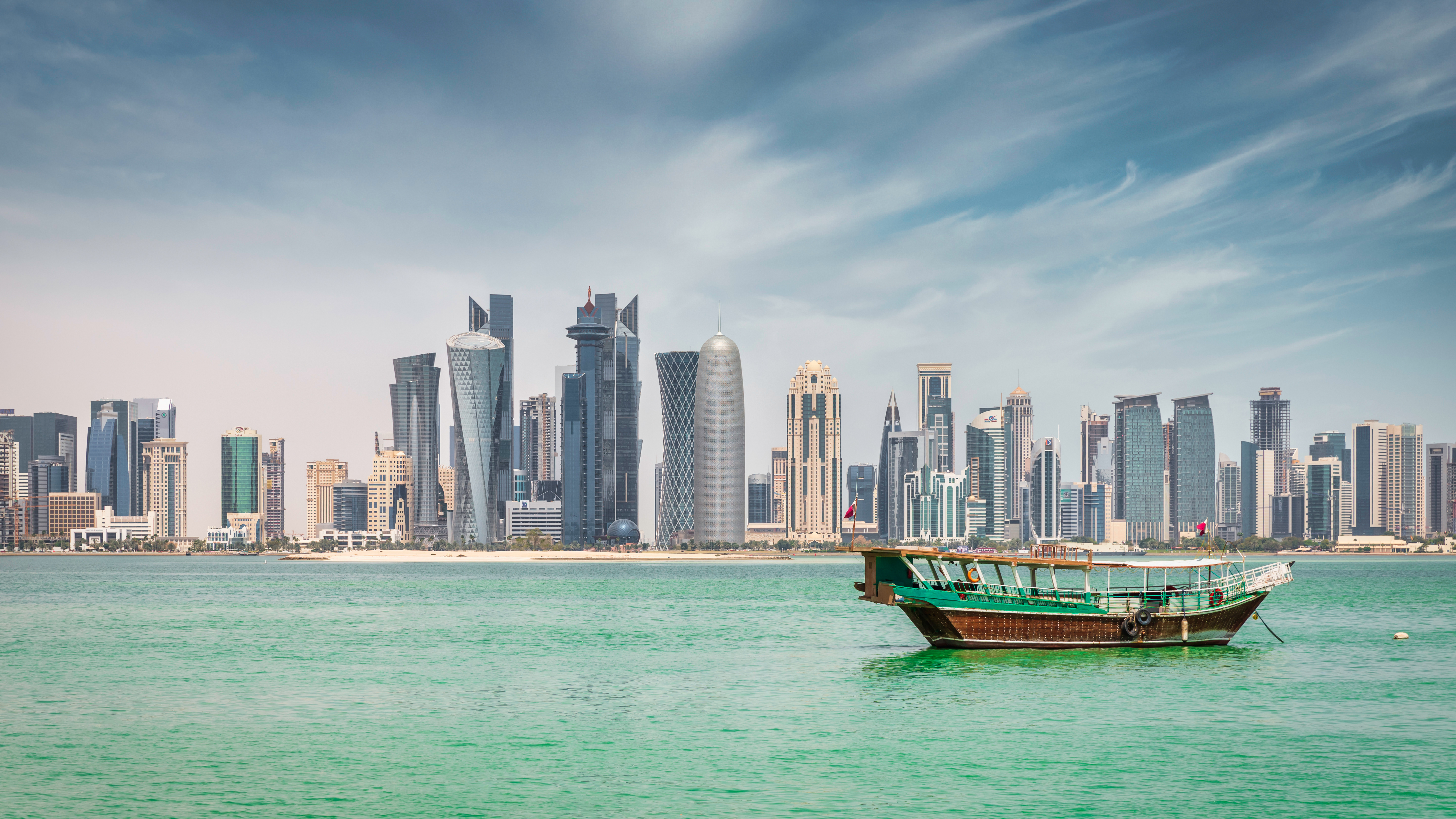 Waterfront panorama at Doha Corniche Promenade with anchored typical qatari Dhow Cruise Boat 