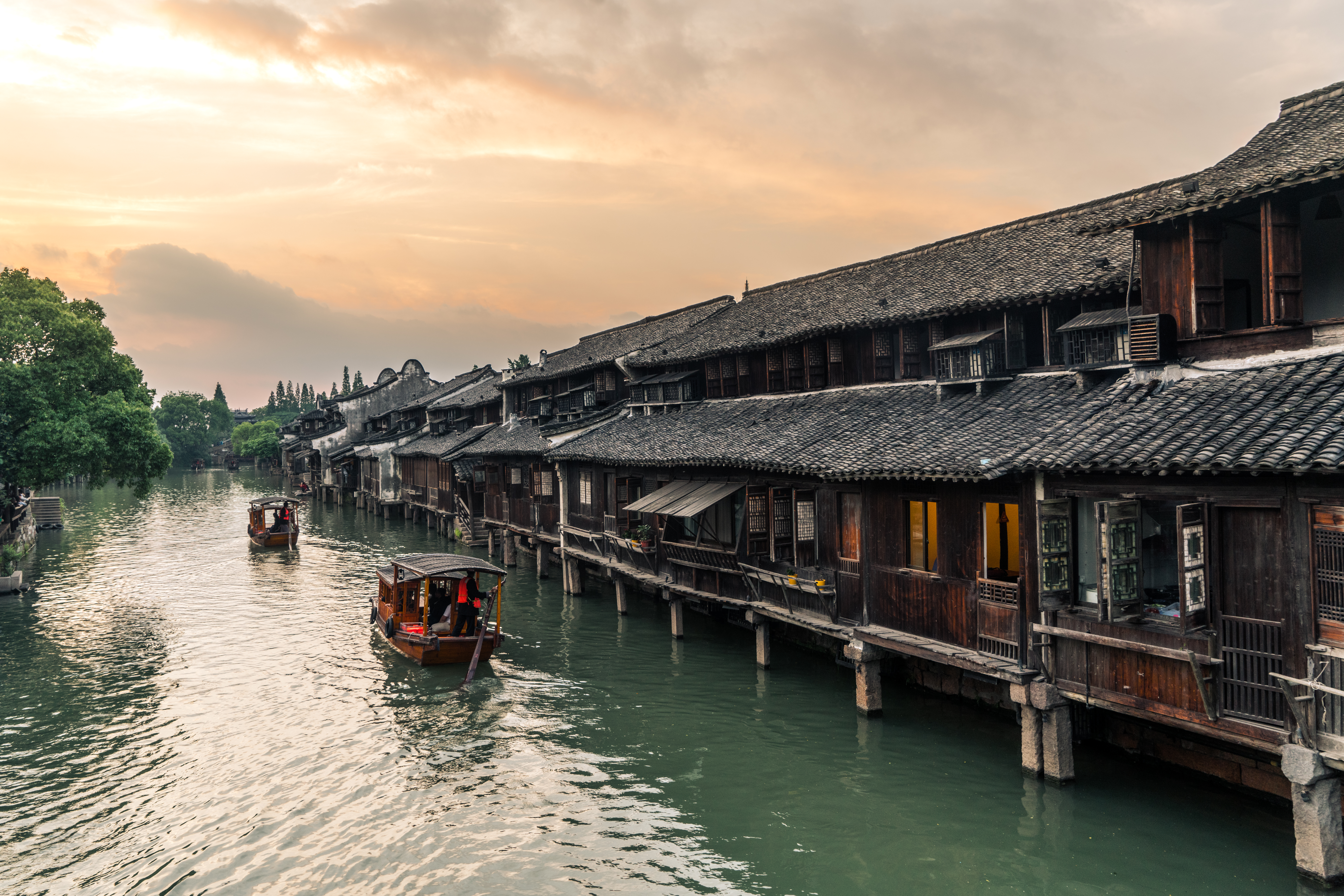 Boats pass by ancient houses along river in Wuzhen, a historic scenic town