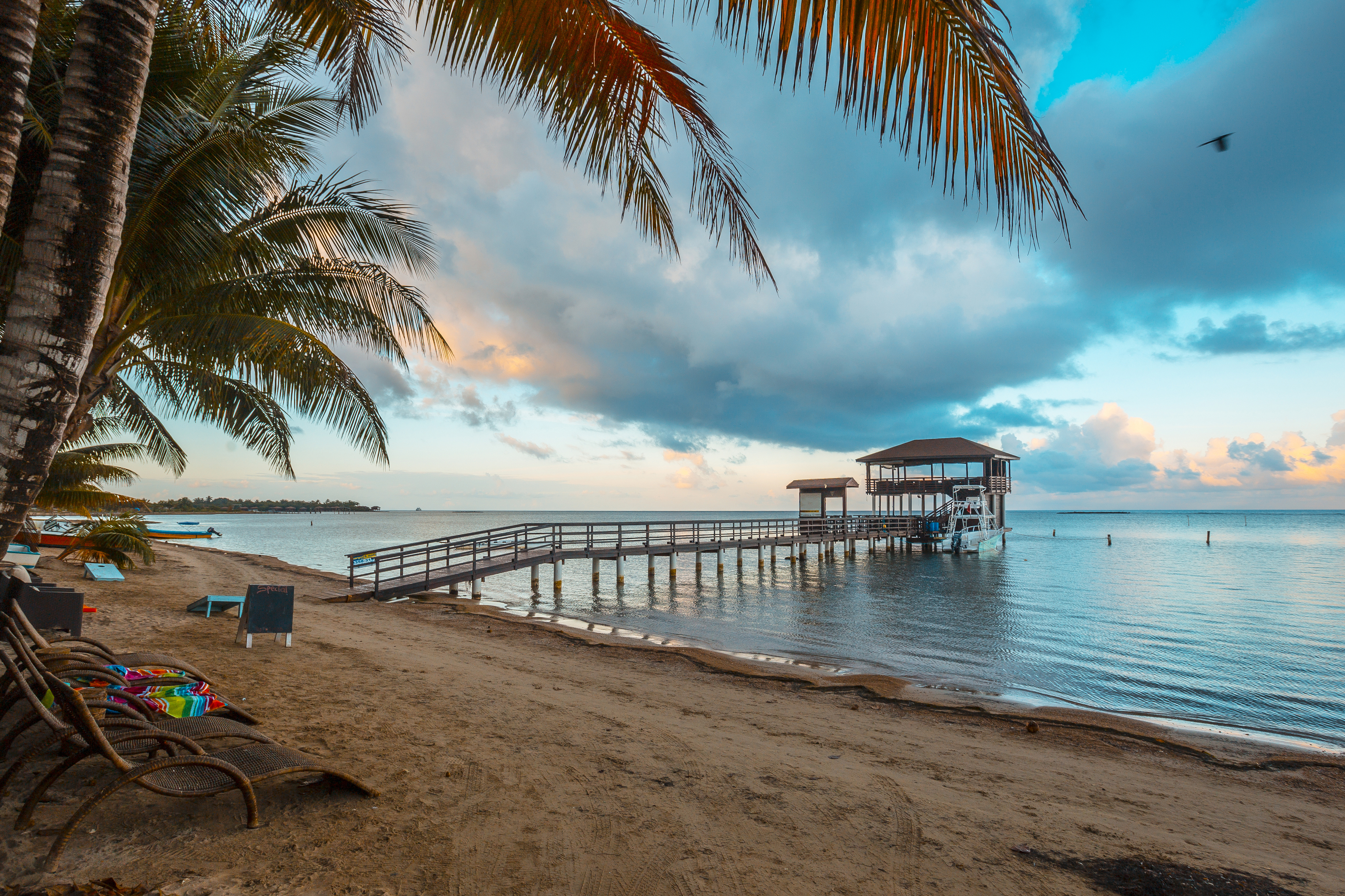 A pier and hut jut out onto the blue calm waters